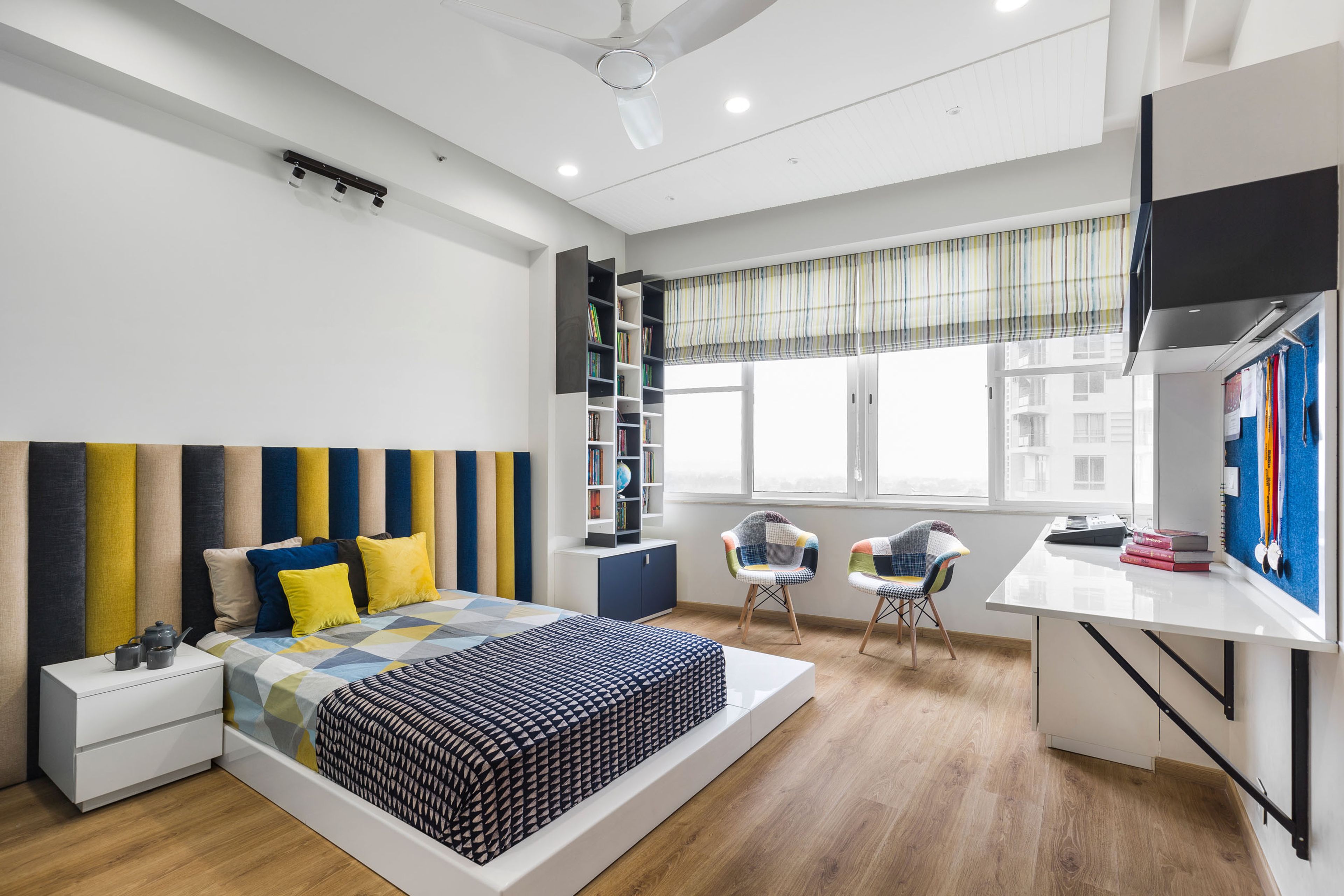 Kids Room With Multicoloured Pipe Headboard, White And Blue Study Table And Multicoloured Accent Chairs - Livspace