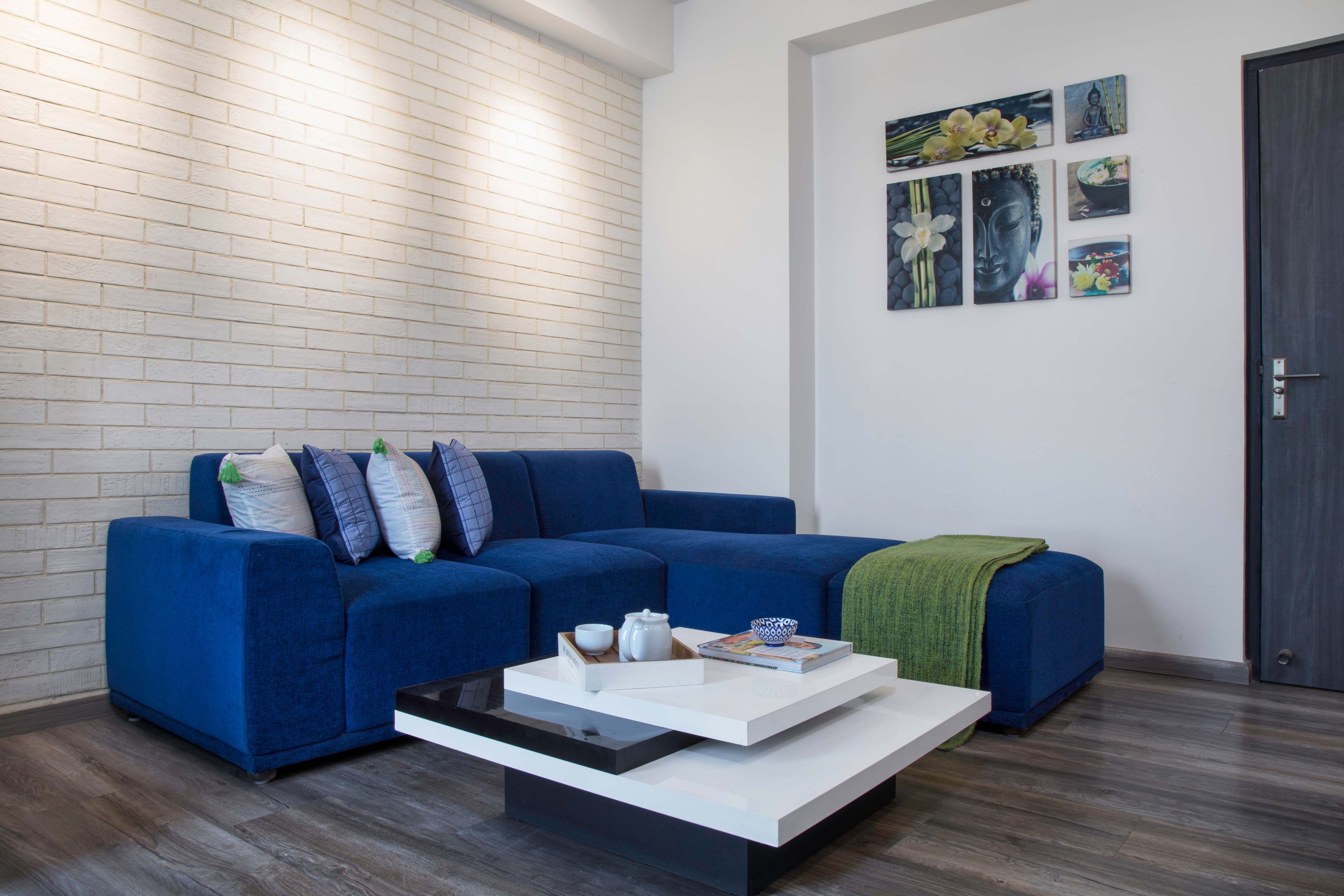 Family Room With Blue L-Shaped Sectional Sofa And White Stacked Coffee Table In Square Shape- Livspace