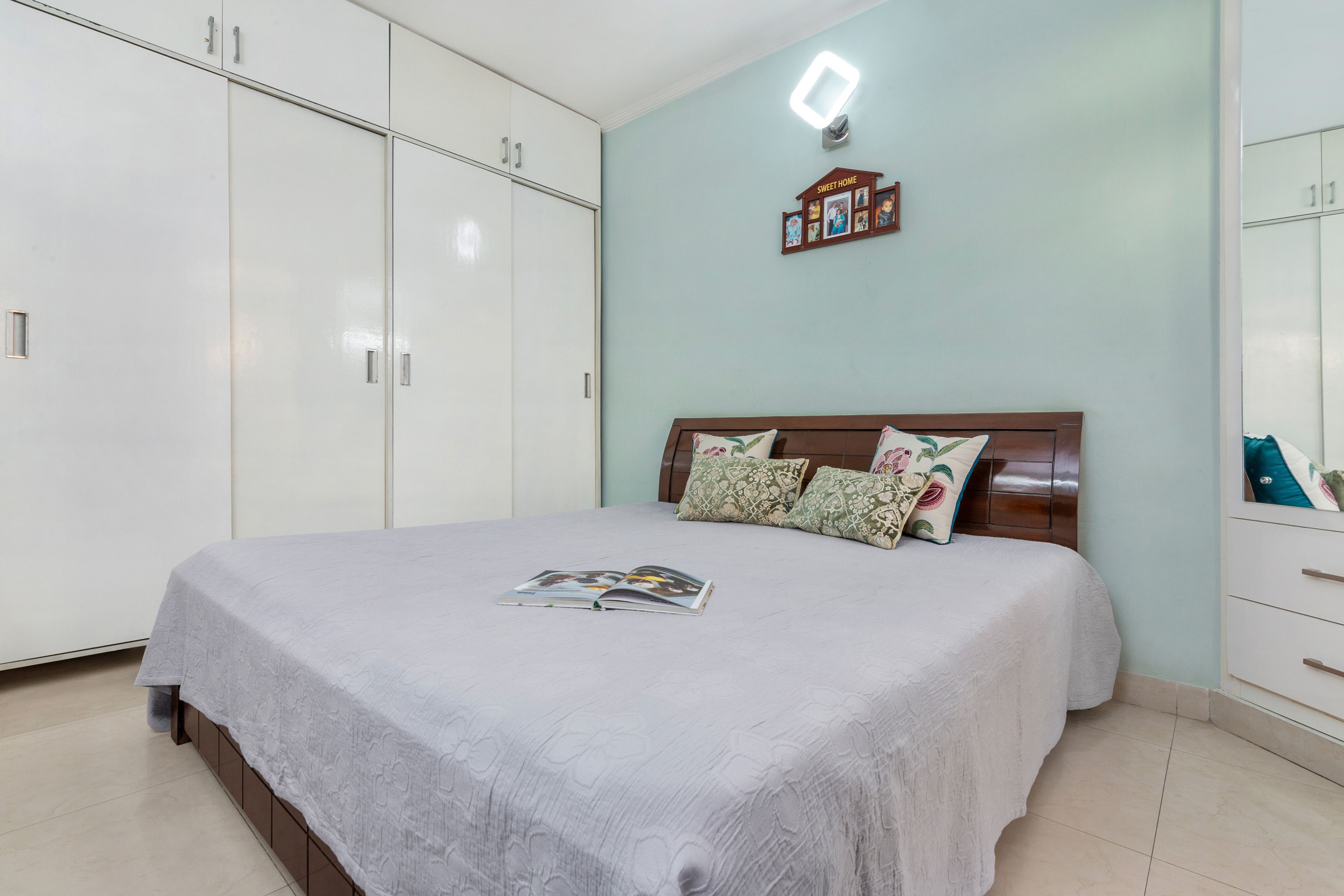 Master Bedroom With Light Blue Accent Wall And 4-Door White Swing Wardrobe - Livspace