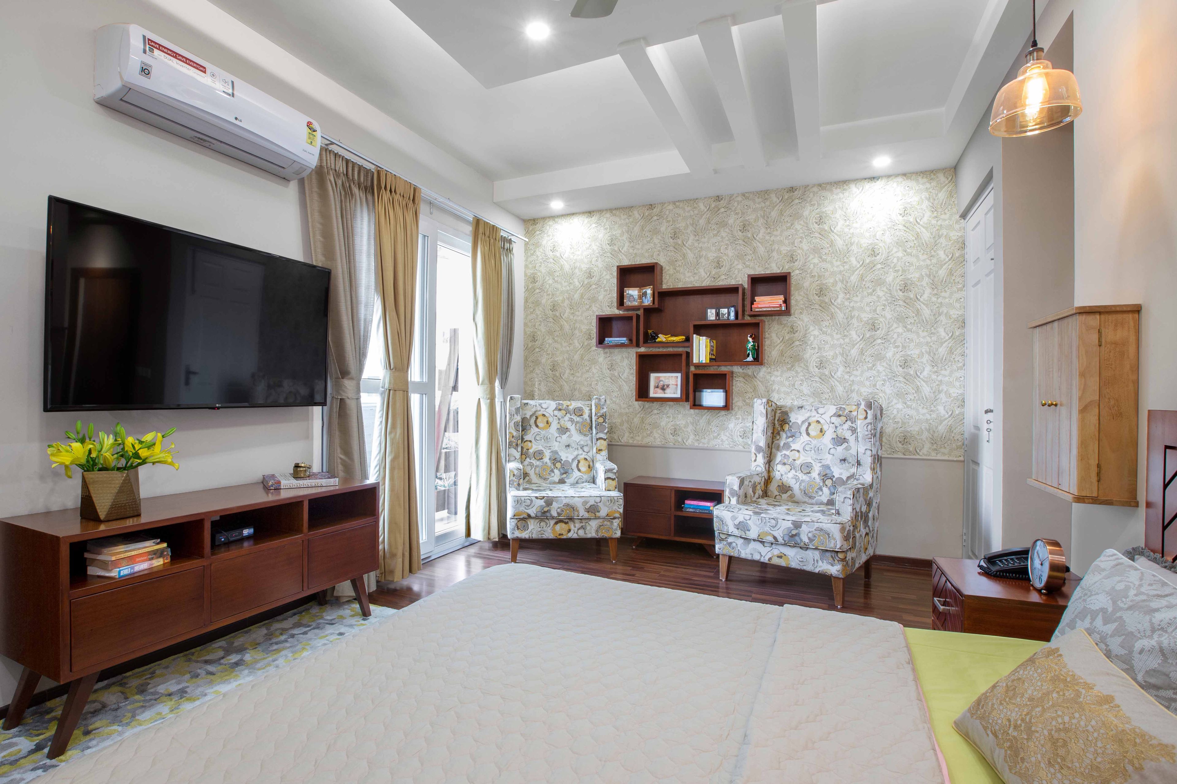 Master Bedroom With Wooden TV Unit, White Patterned Accent Chairs And Beige Abstract Wallpaper - Livspace