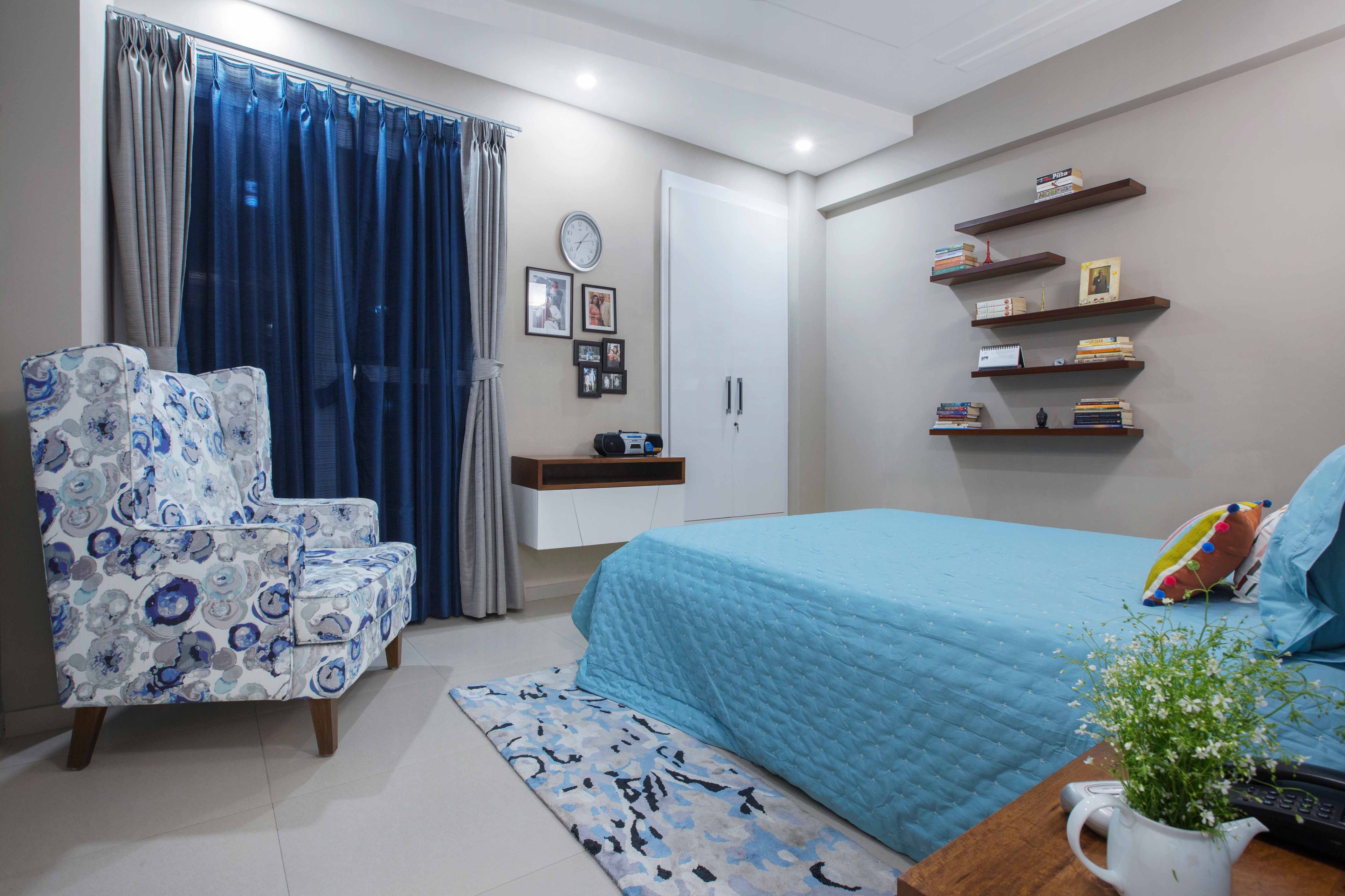 Blue-Themed Guest Room With White And Blue Patterned Chair With Wall Mounted Wooden Shelves - Livspace