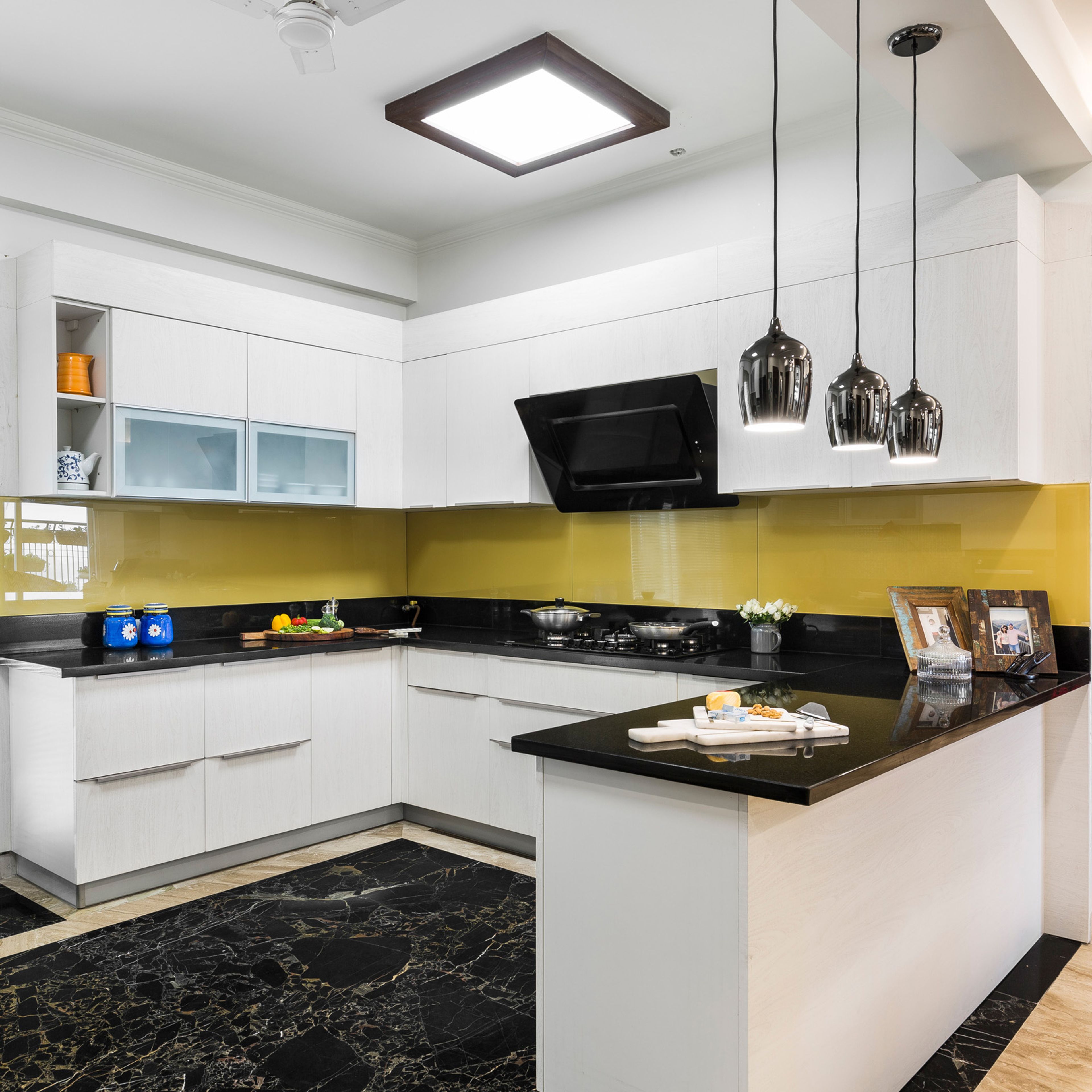 U-Shaped White Kitchen With Yellow Backsplash, Black Countertop, Coffered Ceiling And Black Flooring - Livspace