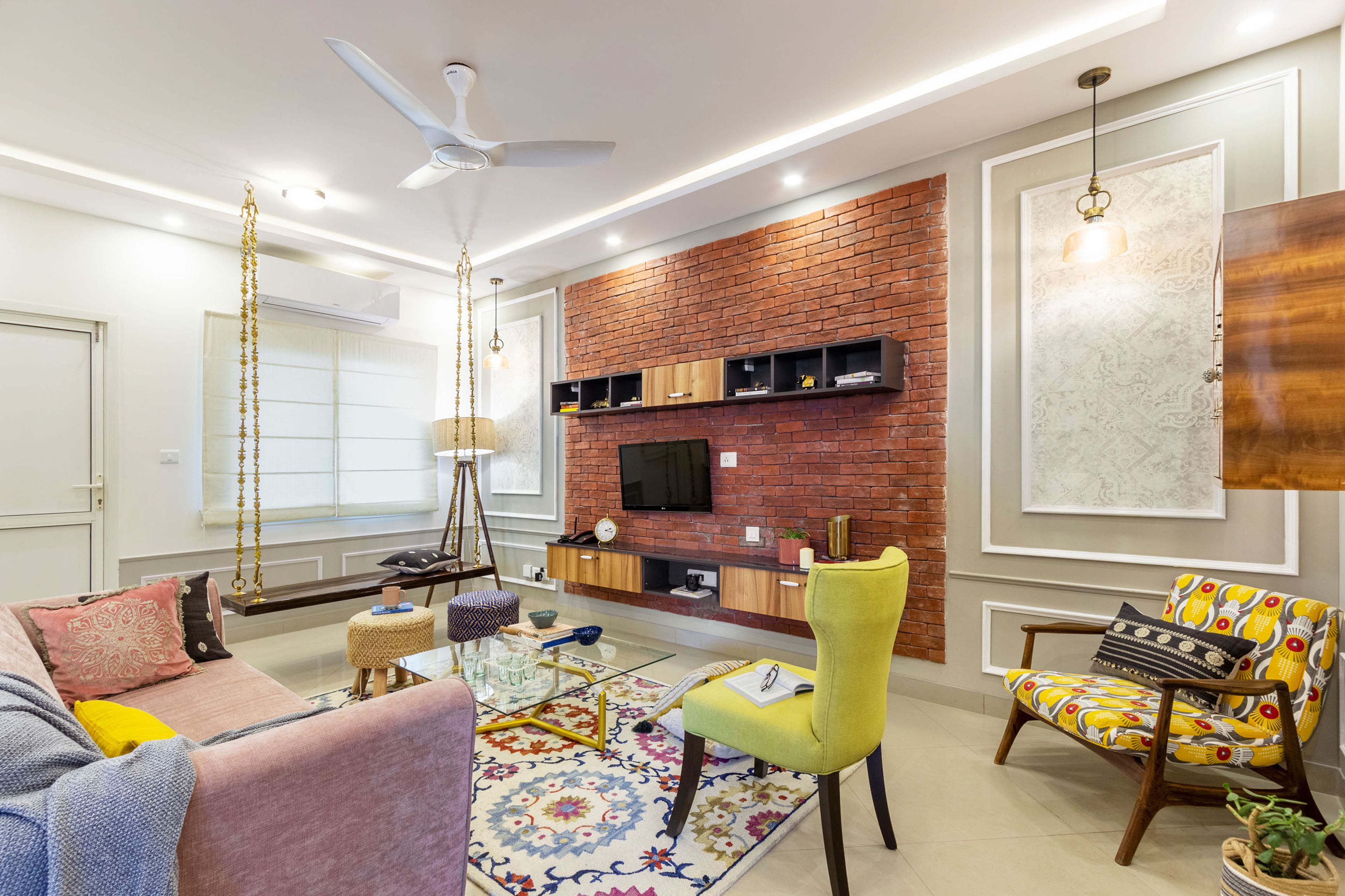 Spacious Living Room With Peach Sofa, Yellow Accent Chair, Wooden Wall-Mounted TV Unit And Red Brick Wall - Livspace