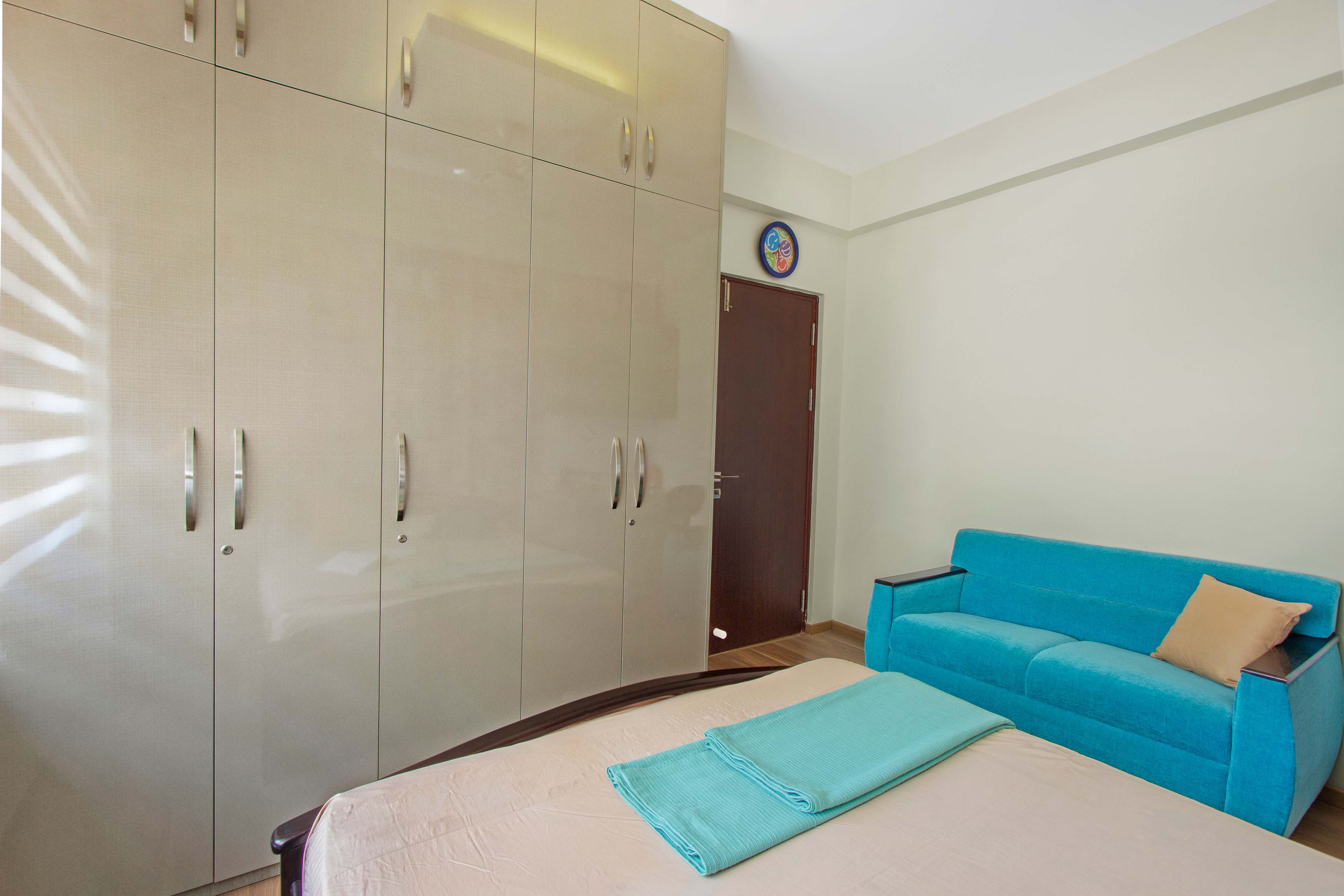 Kids Bedroom Design with 5-Door Beige Swing Wardrobe and Blue 3-Seater Sofa- Livspace