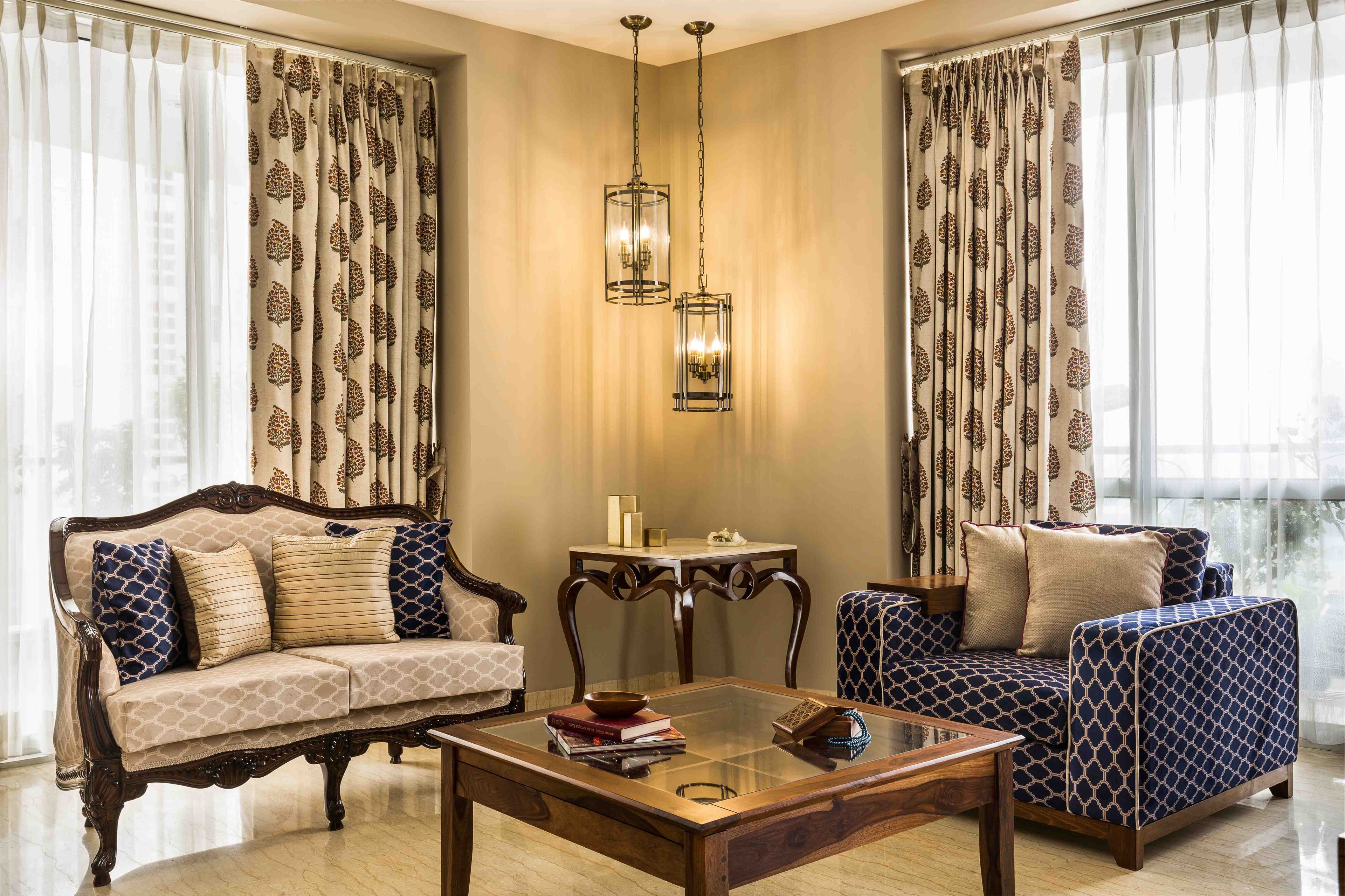 Ambient Living Room With Cabriole Beige Sofe, Blue Track-Arm Accent Chair And Pendant Lights - Livspace