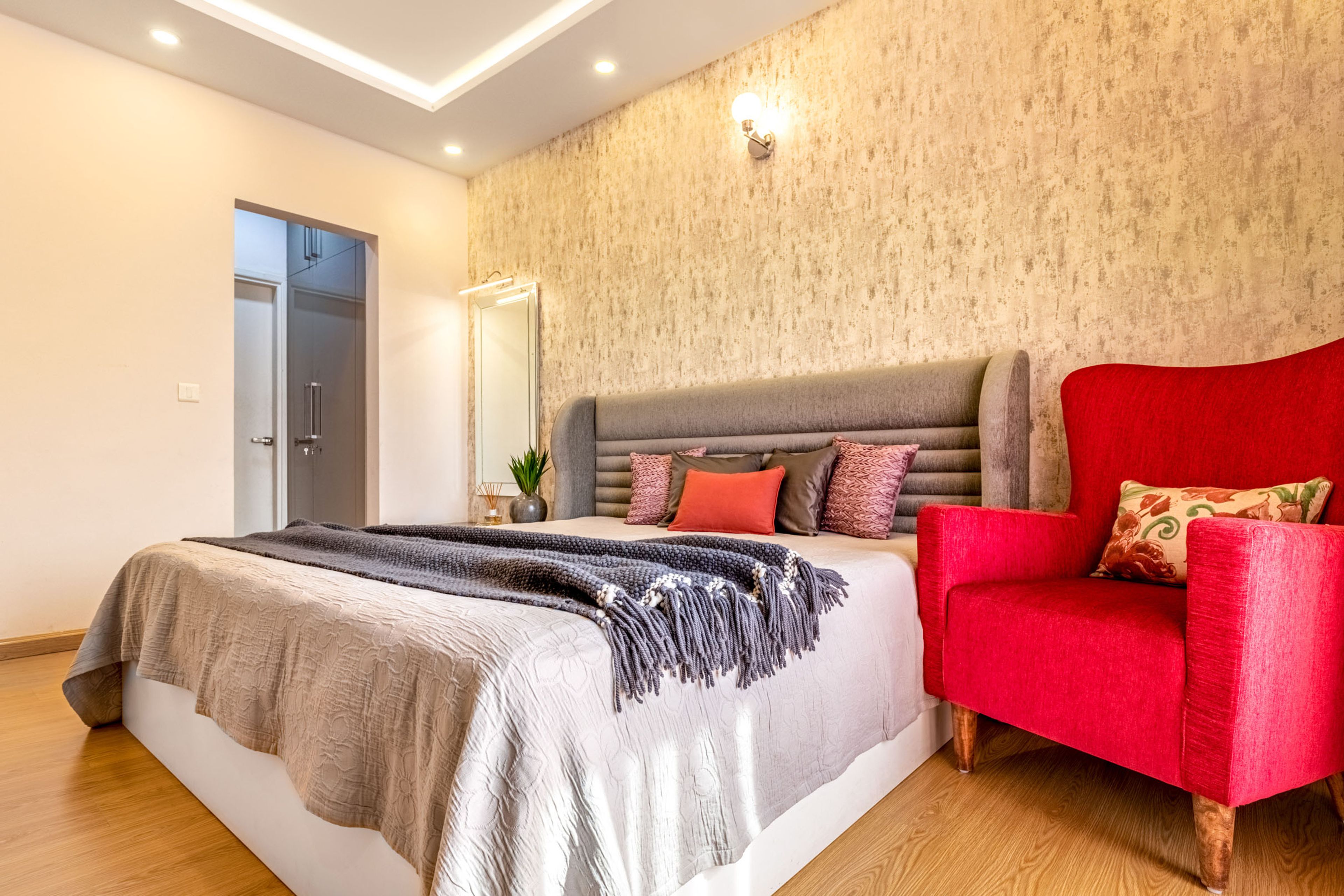 Beige Master Bedroom Design WIth Red Accent Chair - Livspace