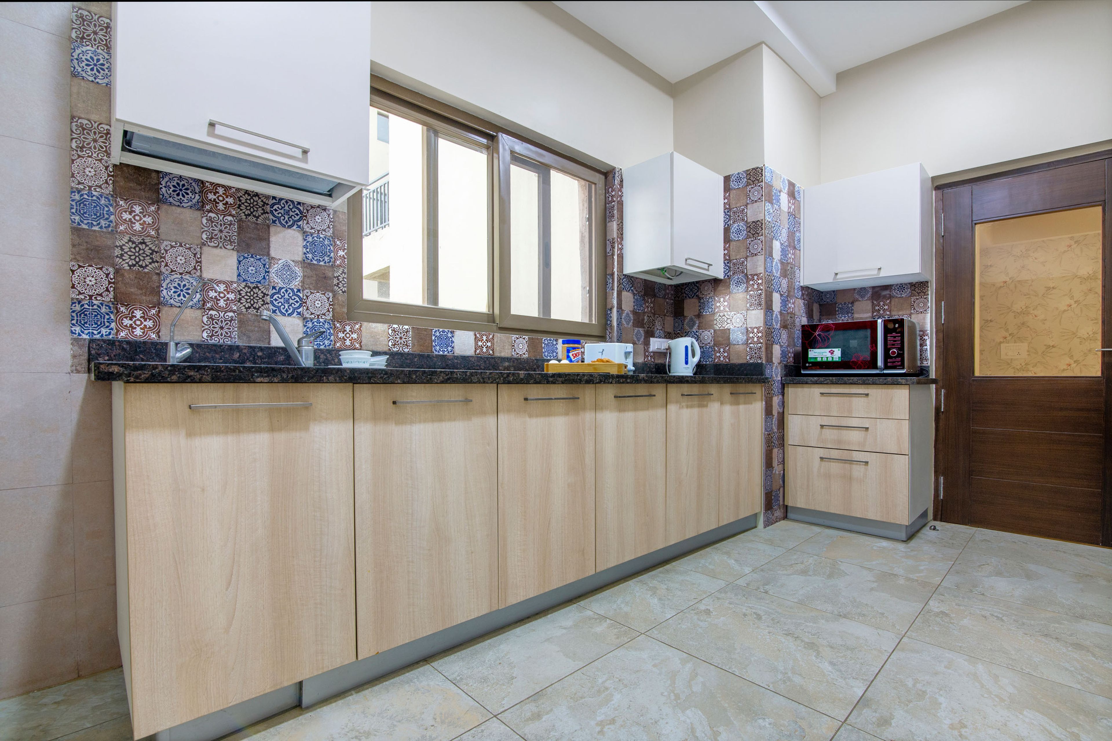 White And Wood Kitchen Cabinet Design With Moroccan Dado Tiles And Oven Unit - Livspace