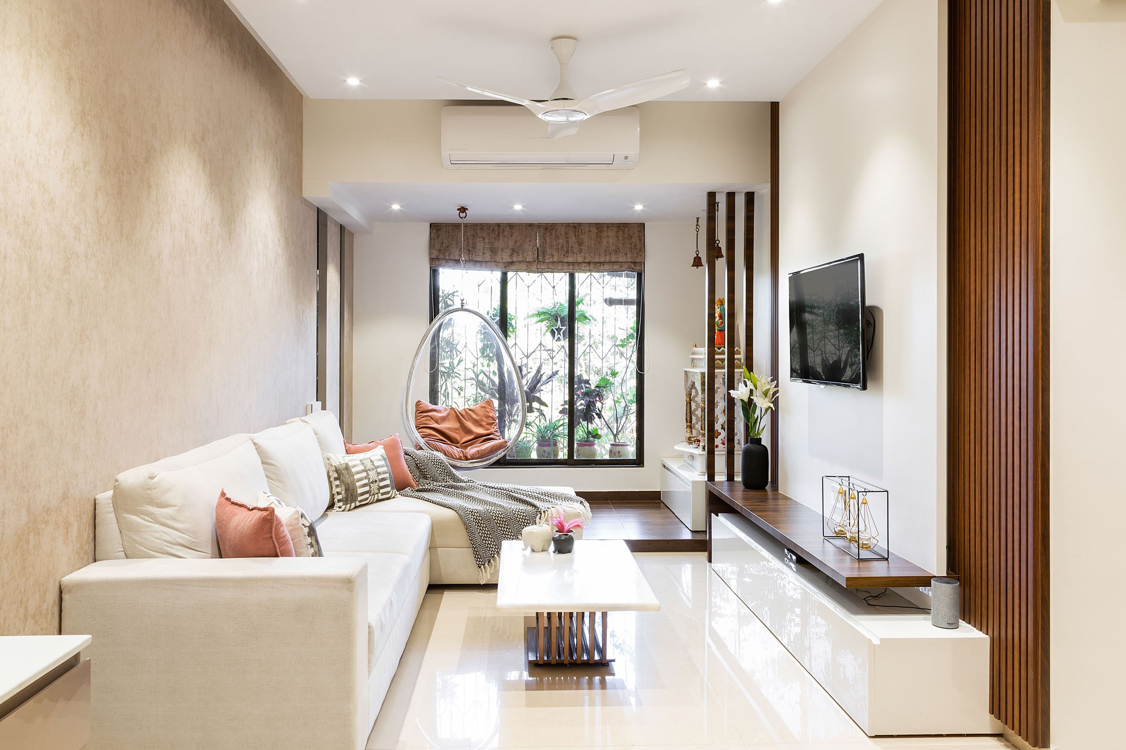 Spacious Living Room Design With L-Shaped Sectional Sofa, White And Wood TV Console, Integrated Mandir Unit And Beige Patterned Wall - Livspace