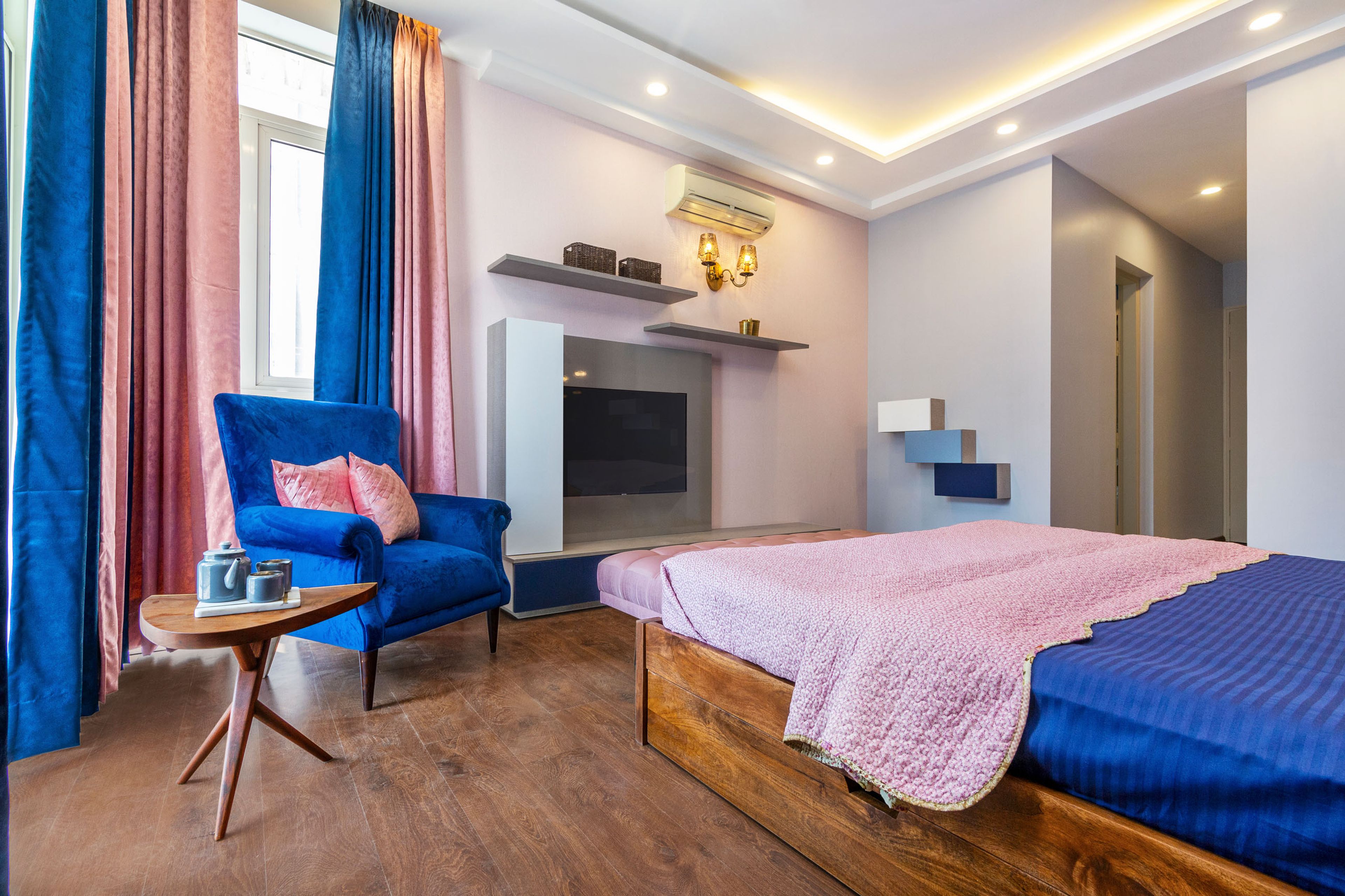 Master Bedroom With Floor-Mounted TV Console And Blue Accent Chair - Livspace