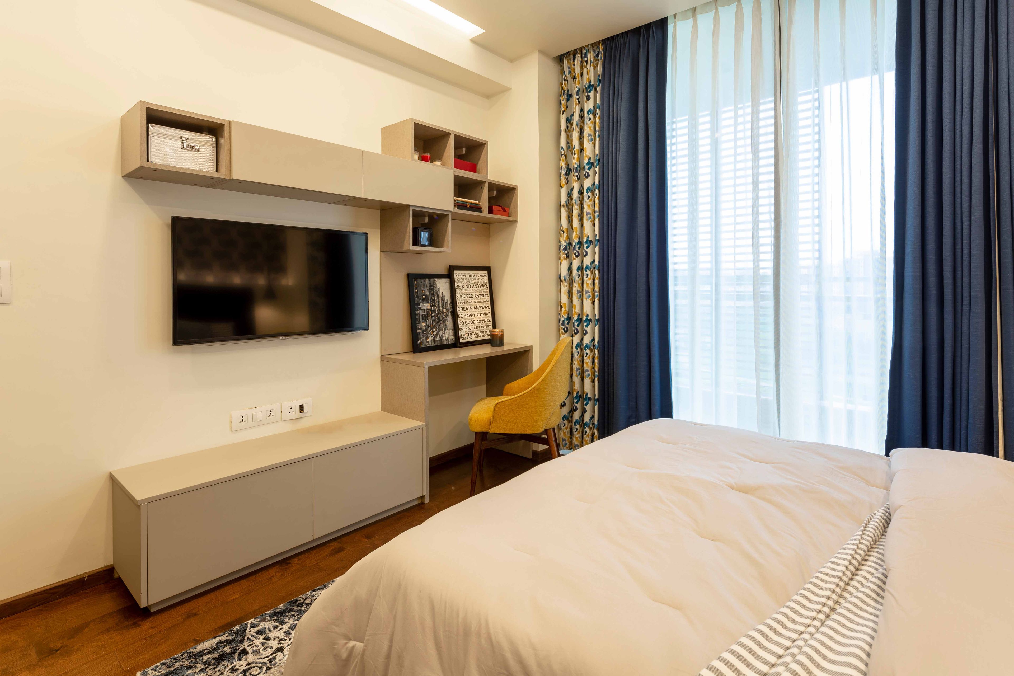 Master bedroom with beige floor-mounted TV unit and study unit - Livspace