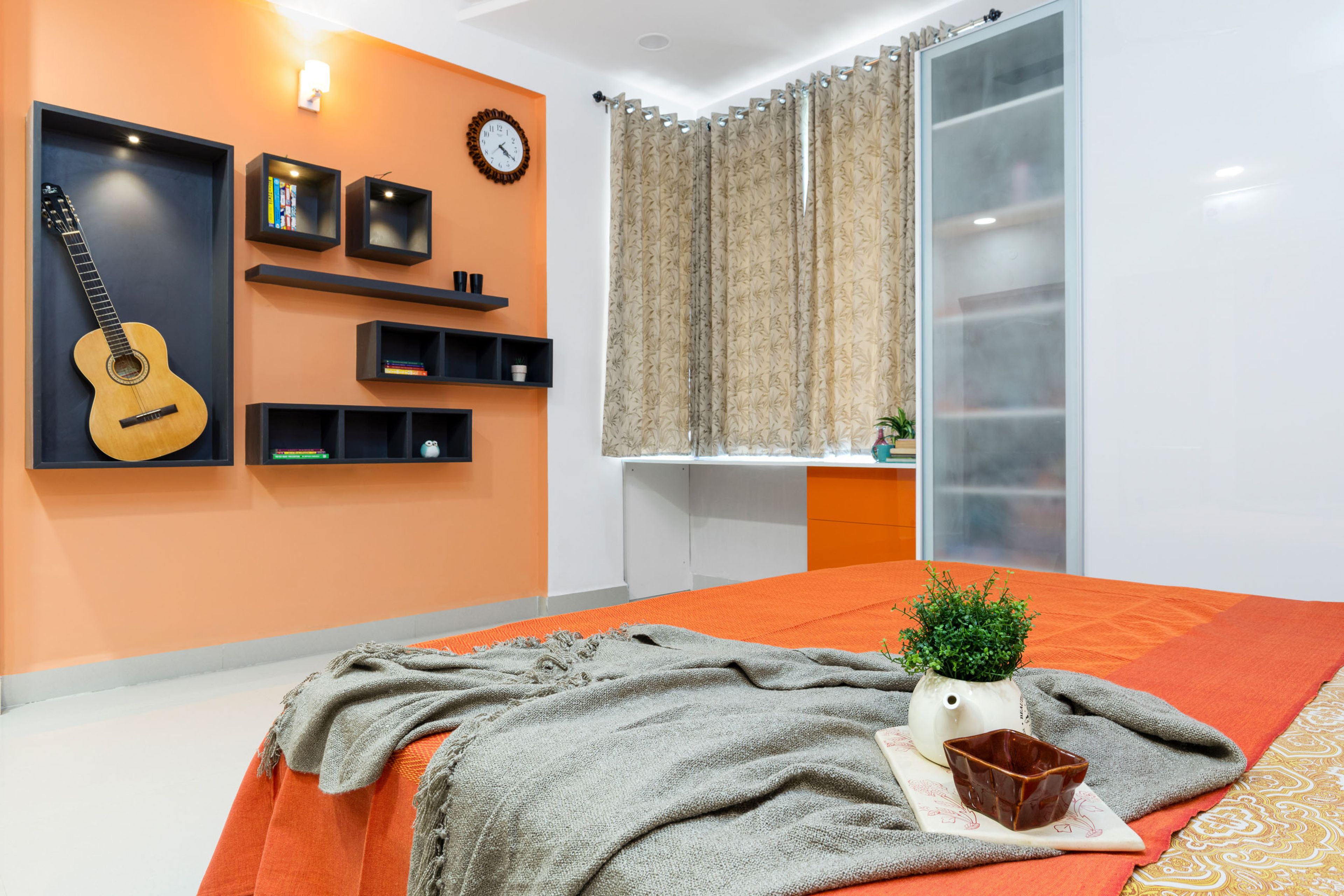 Master Bedroom With Orange Accent Wall And Black Shelves, Orange And White Study Table And Wardrobe - Livspace
