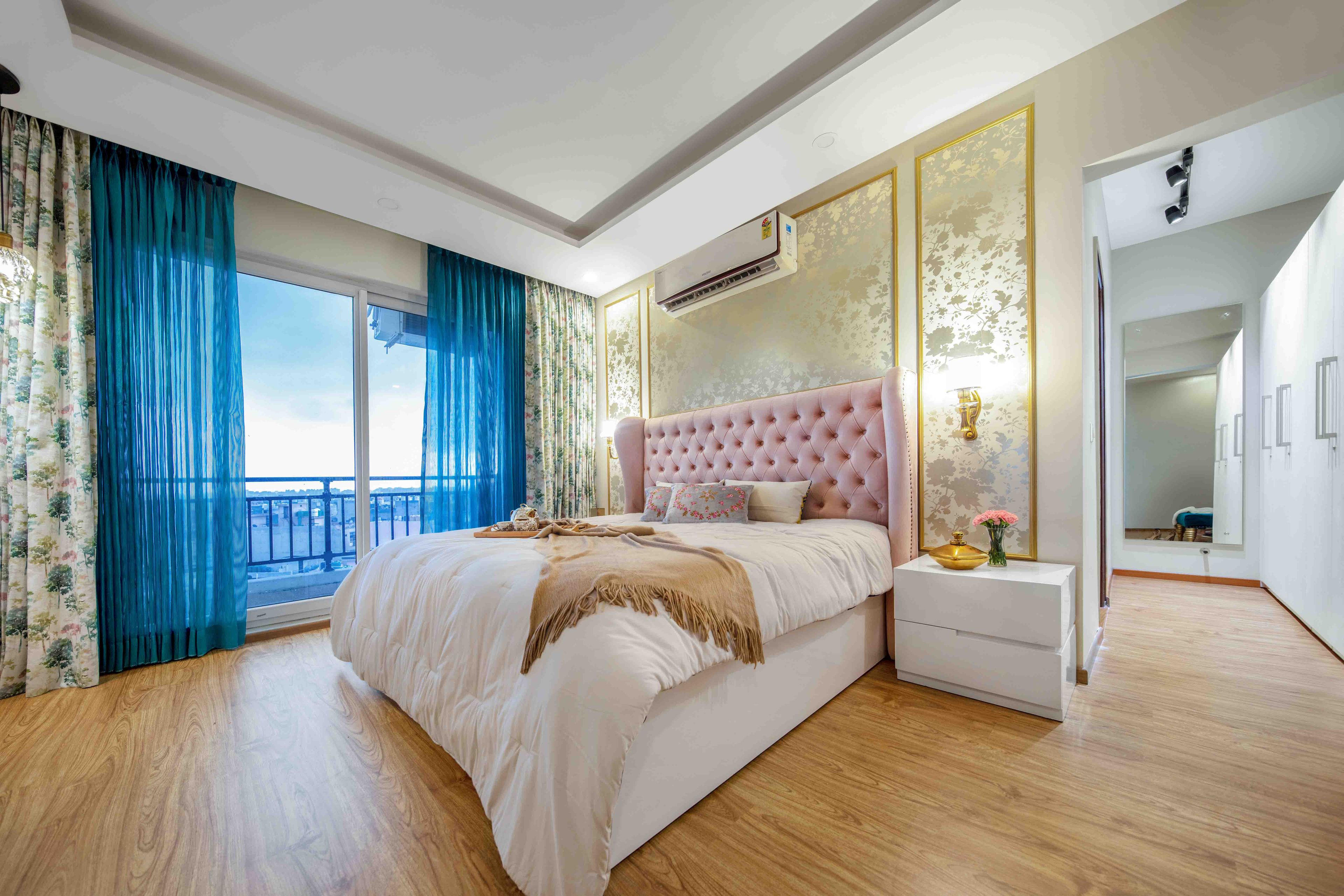 Spacious Bedroom Design With Queen-Size Bed And Pink Headboard, Beige Floral Wallpaper And 5-Door White Swing Wardrobe- Livspace