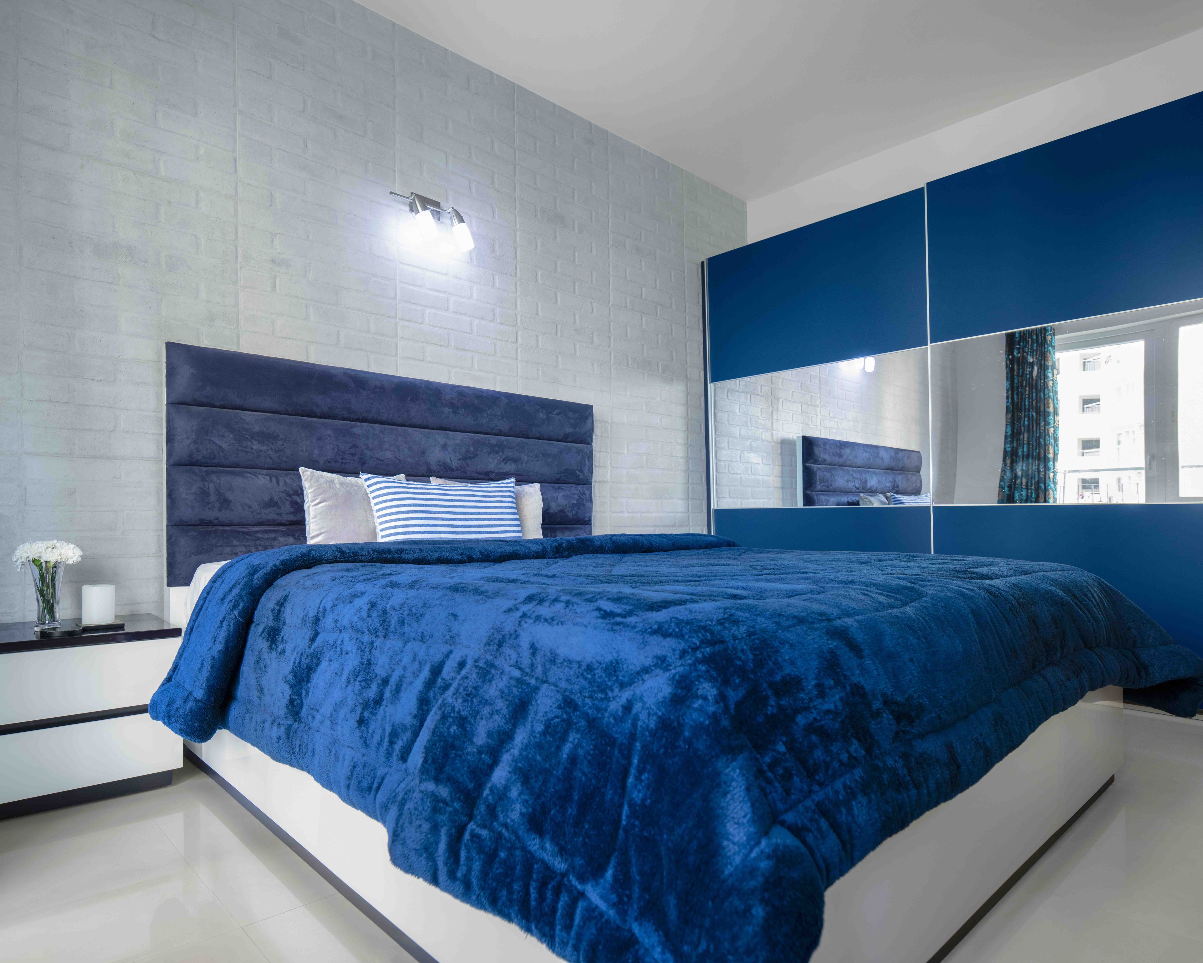 Master Bedroom Design With 2-Door Blue Sliding Wardrobe, Queen-Size White Bed With Blue Headboard And White Brick Wallpaper - Livspace