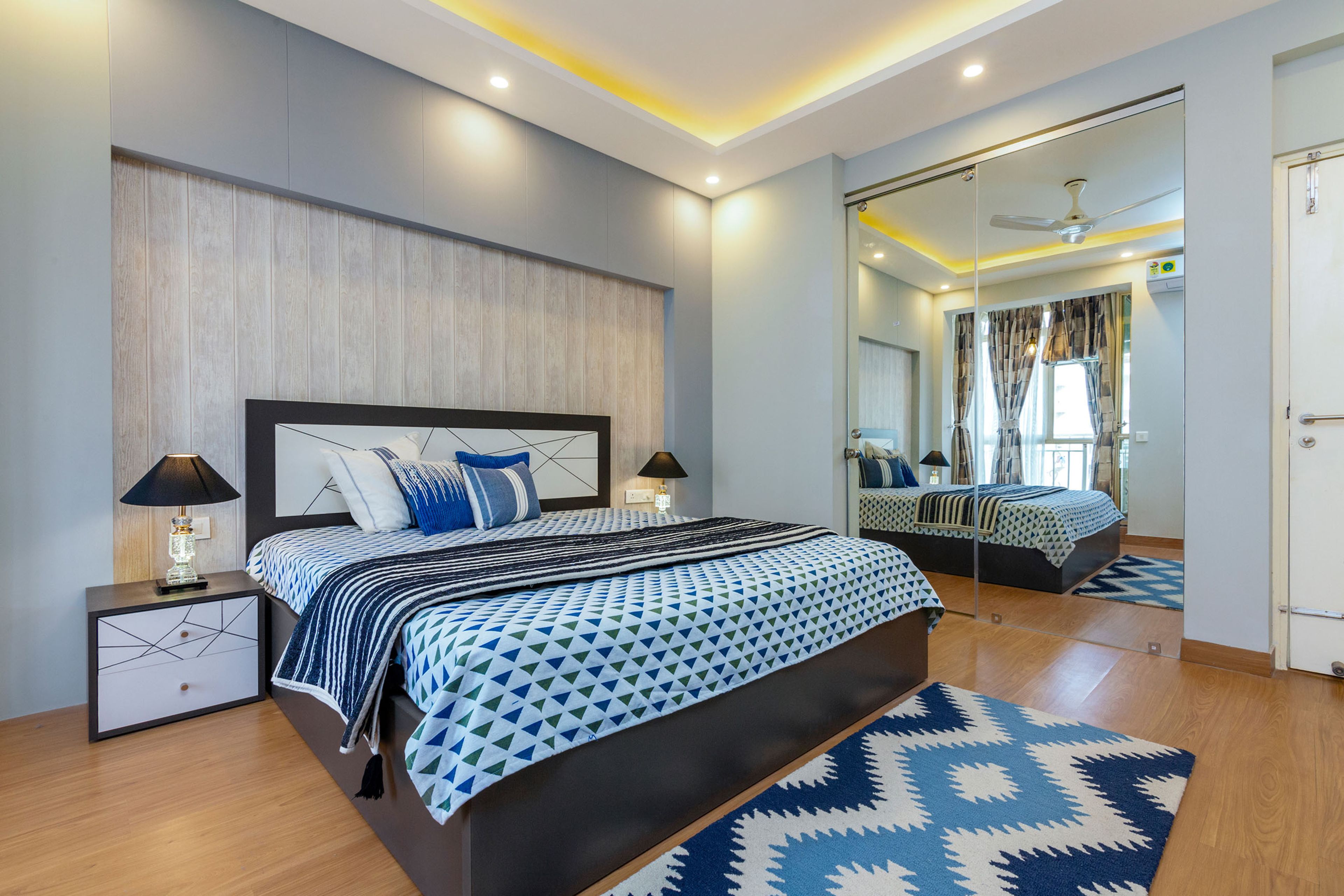 Master Bedroom Design With Black And White Bed, Side Tables, 2-Door Sliding Mirrore Wardrobe And Grey-Beige Accent Wall With Woden Panels - Livspace