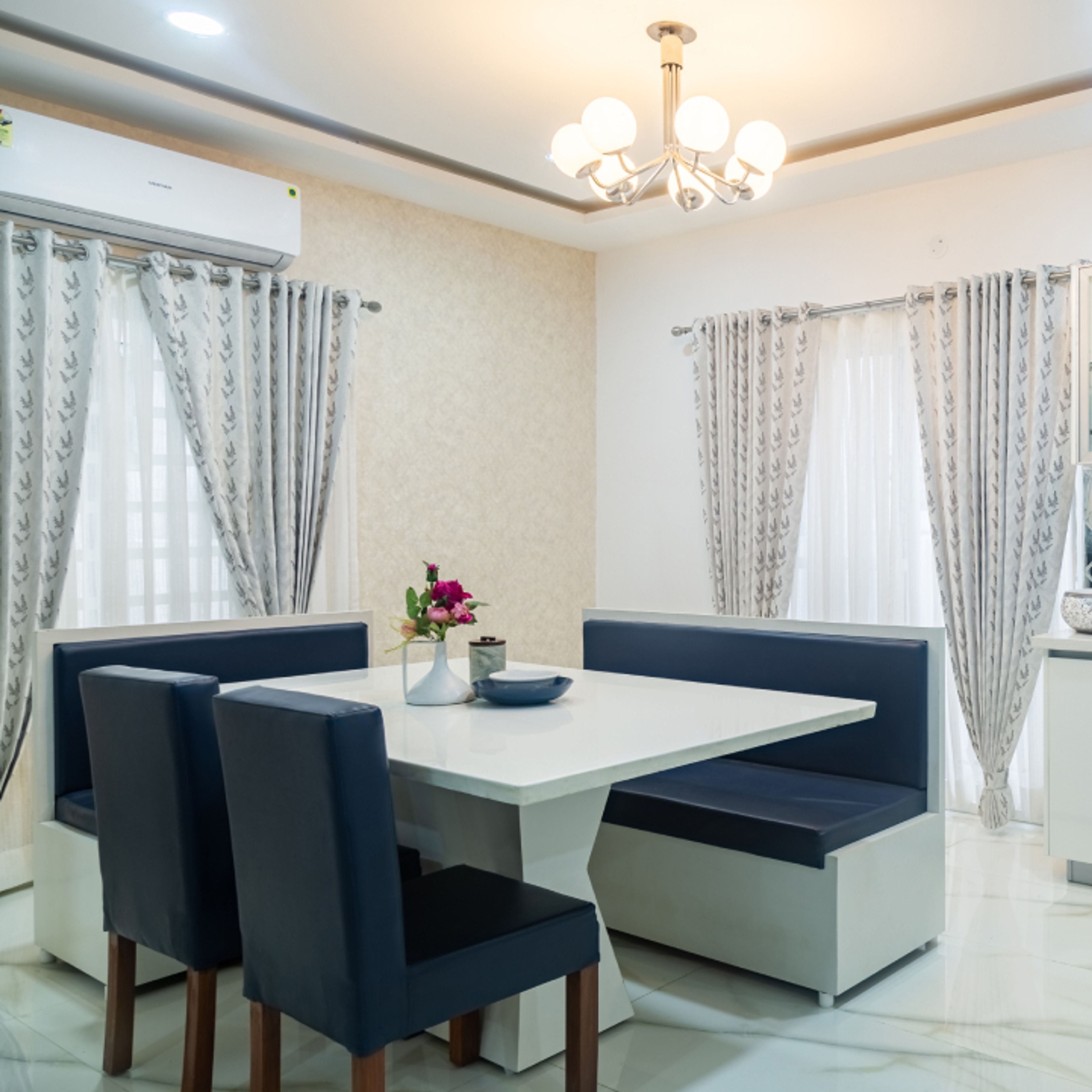 6-Seater Dining Room Design With A White Table And An Elegant Chandelier - Livspace