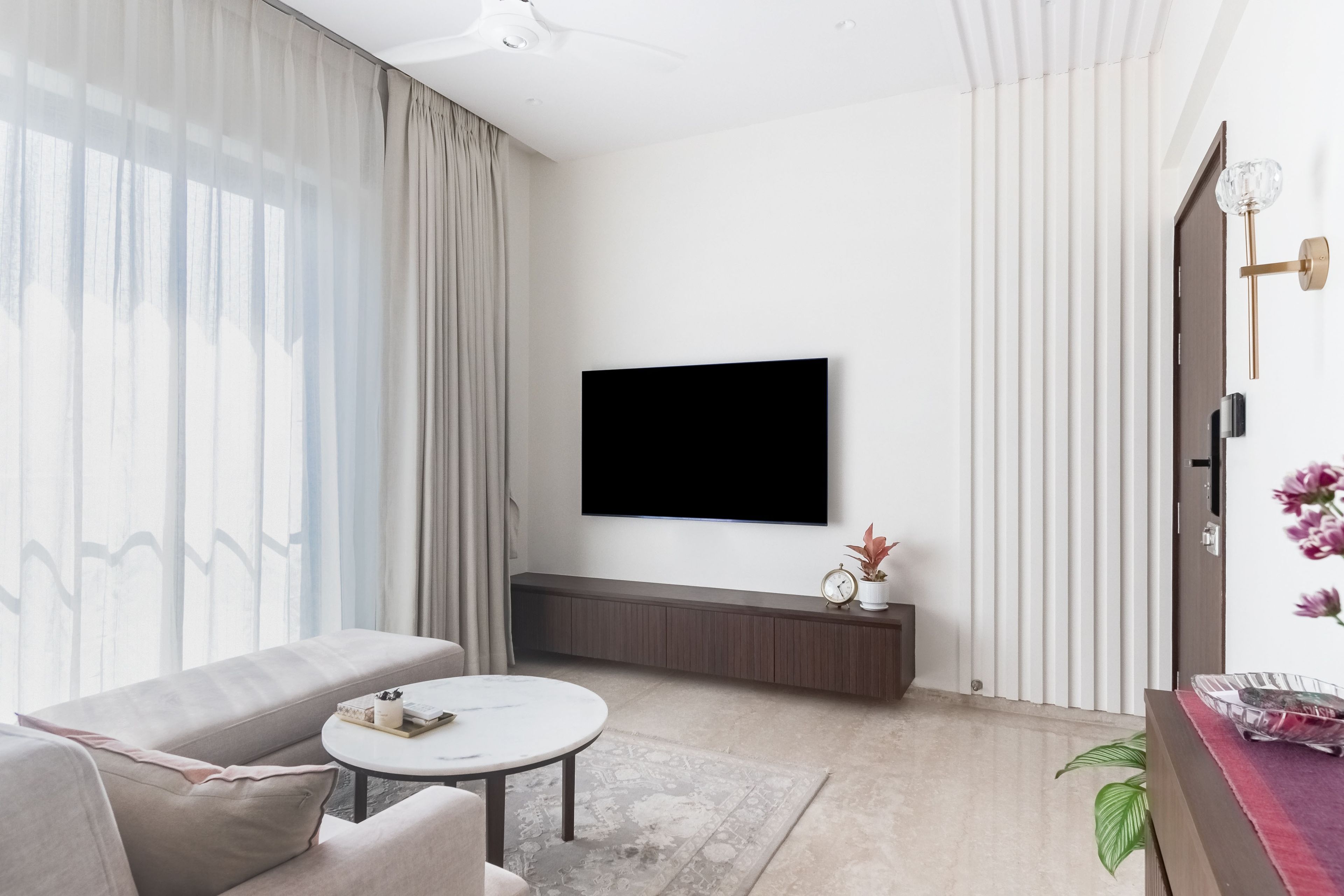White living room with PoP wall panel and wall mounted TV with storage cabinet - Livspace