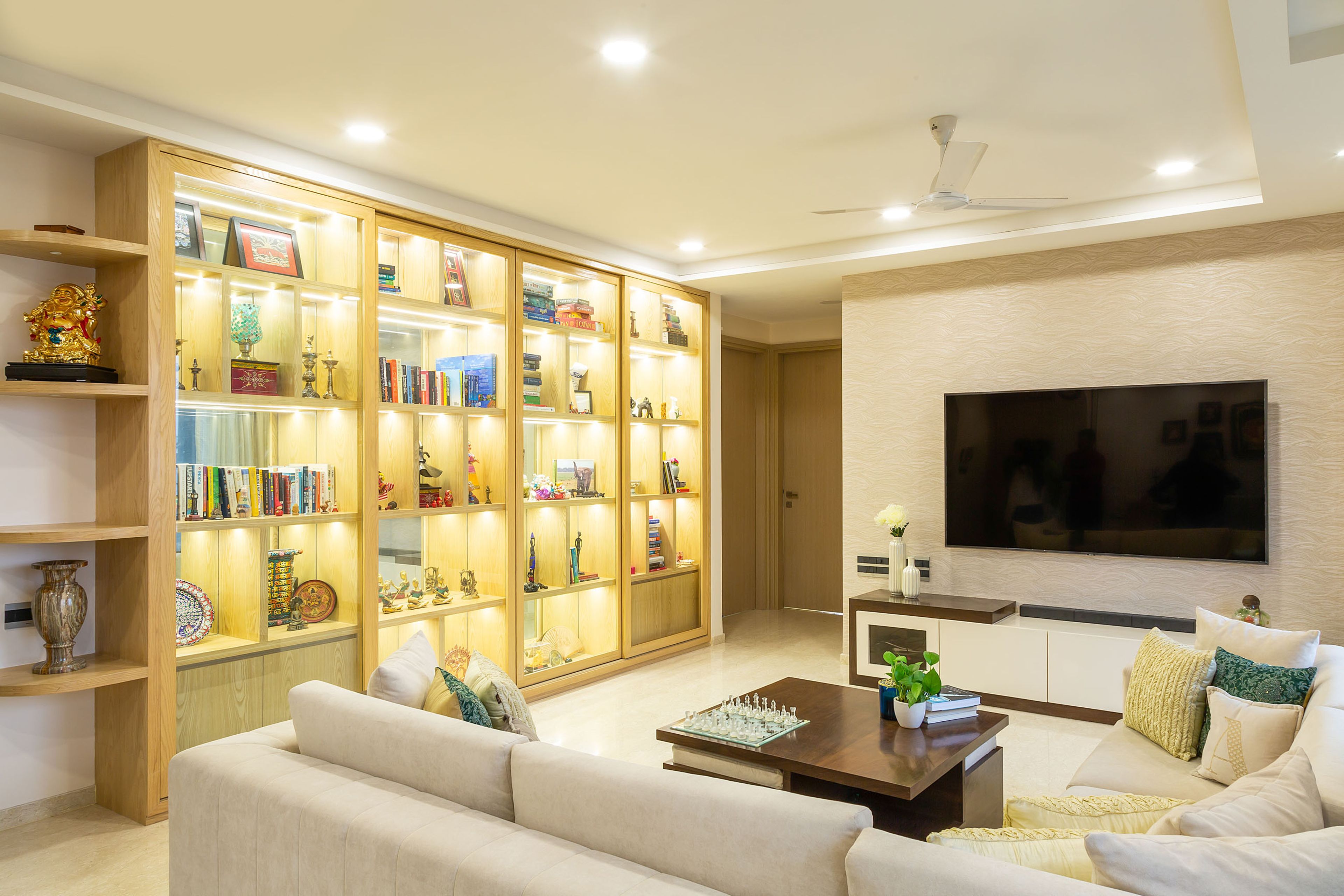 Large wooden bookshelf and storage unit lined with LED lights - Livspace