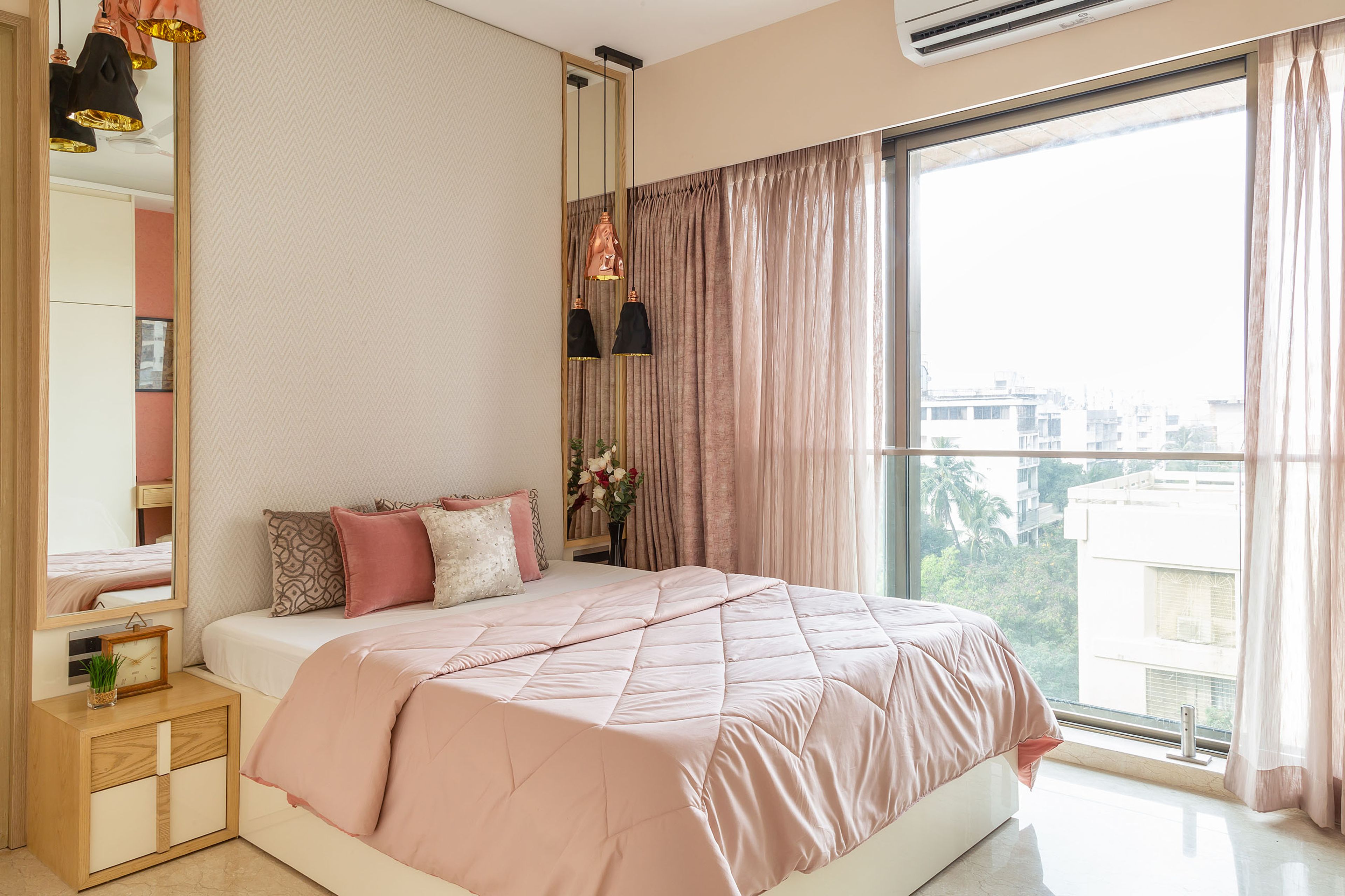 Pink and white master bedroom design with wooden storage unit - Livspace