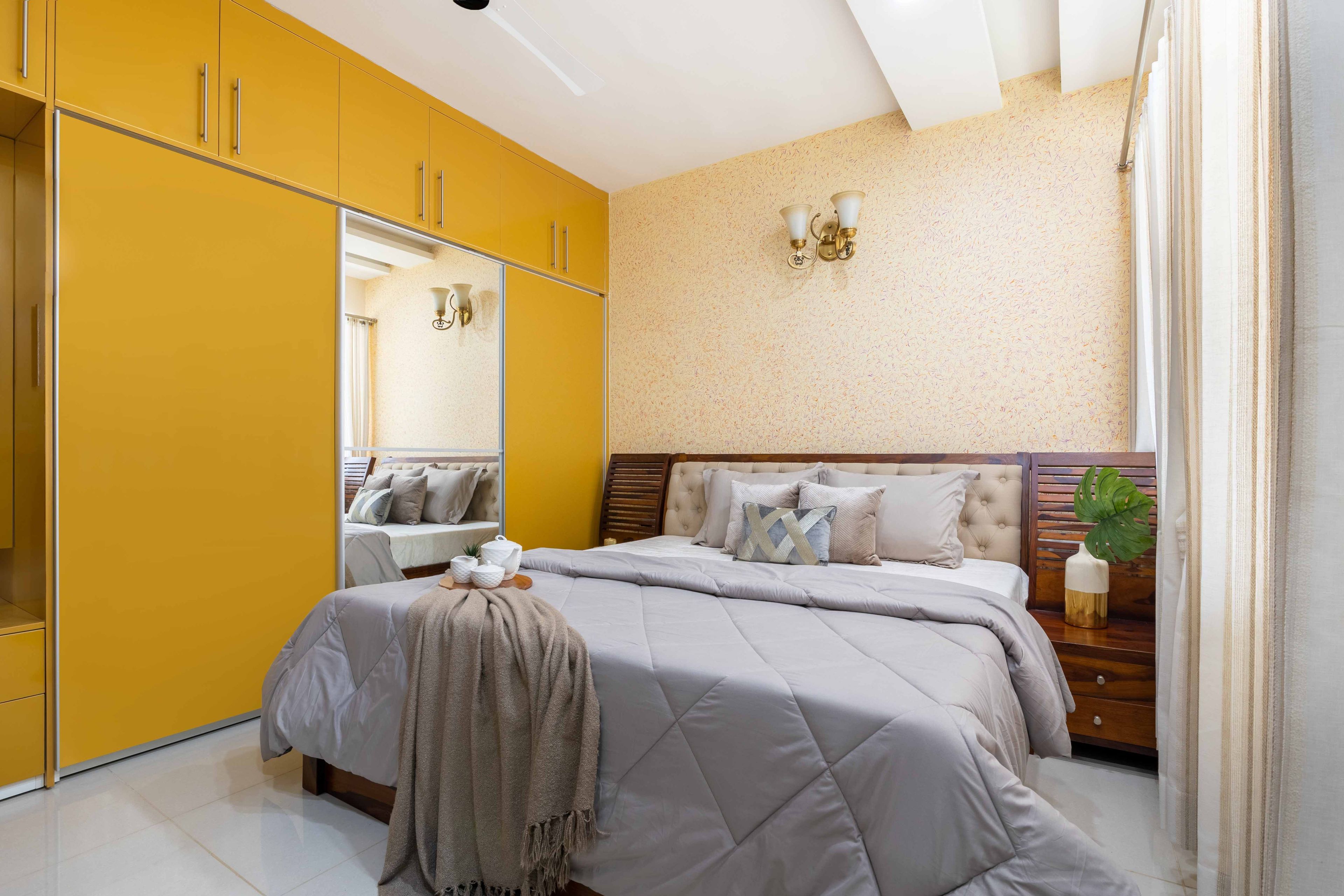 Wooden bed and 3-door yellow wardrobe for the master bedroom - Livspace