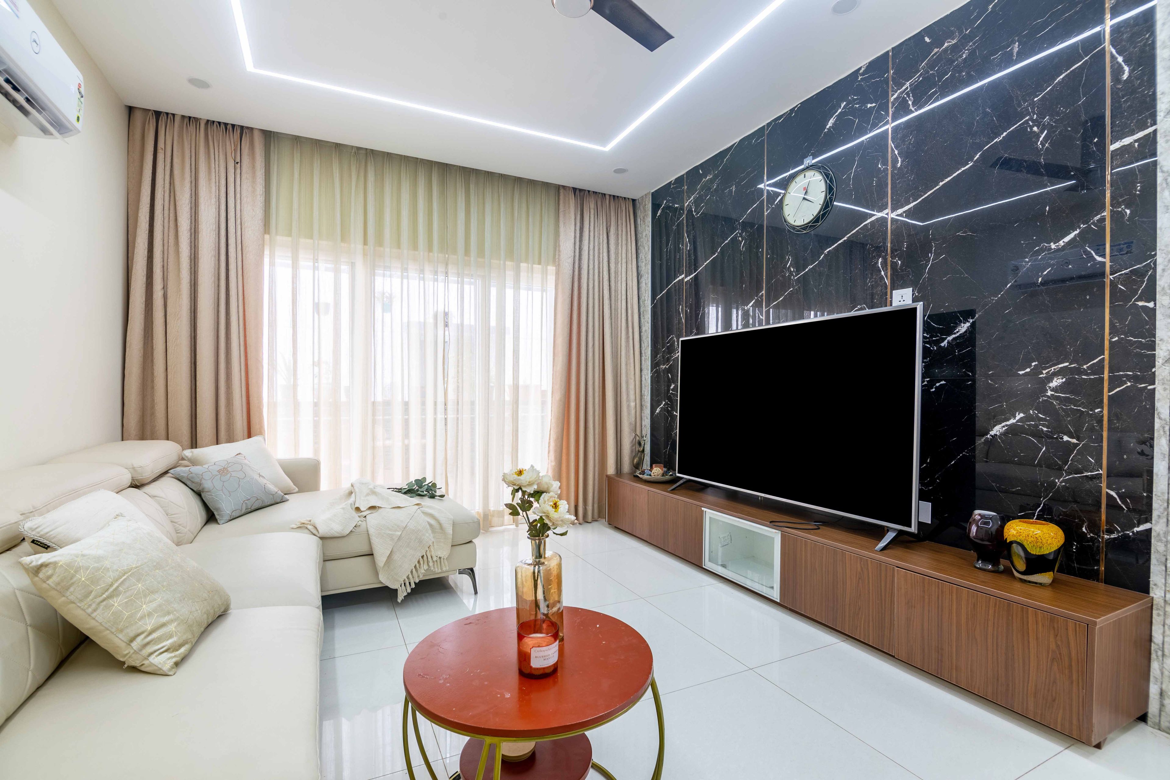 Living room with wood and marble TV unit and off-white sectional sofa - Livspace