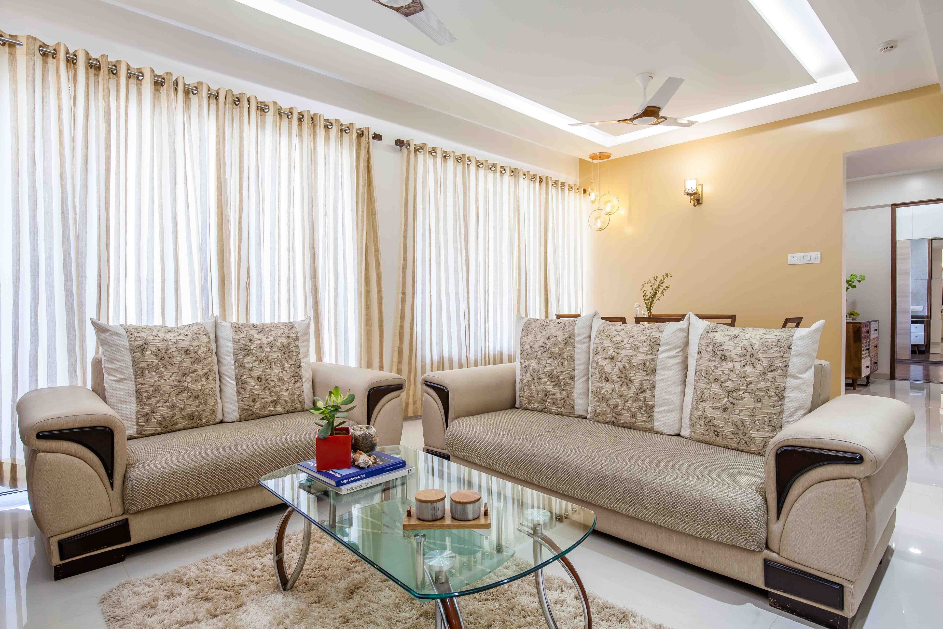 Beige L Shaped sofas with glass coffee table - Livspace