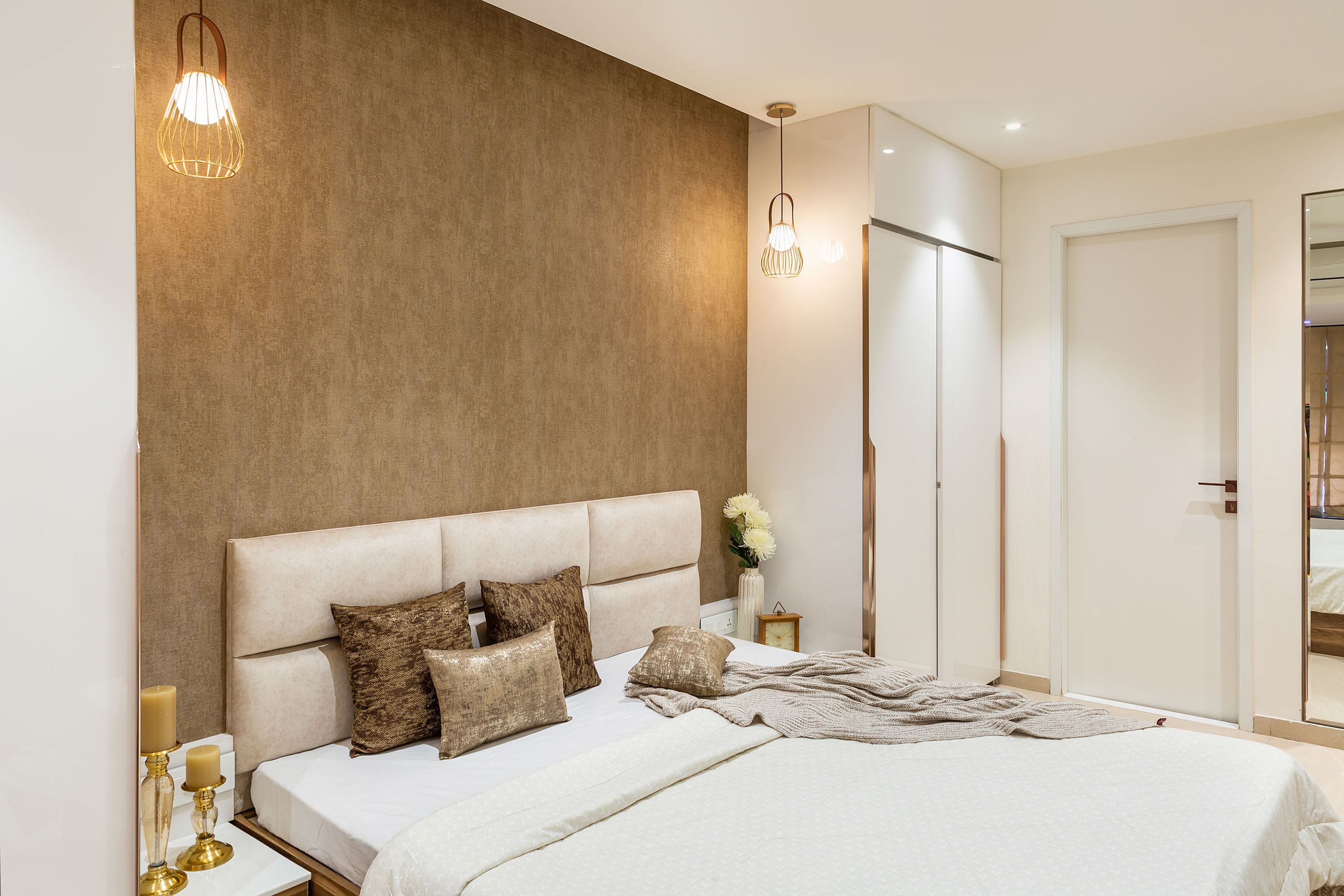 White and brown master bedroom with beige tufted headboard and brown pillows - Livspace