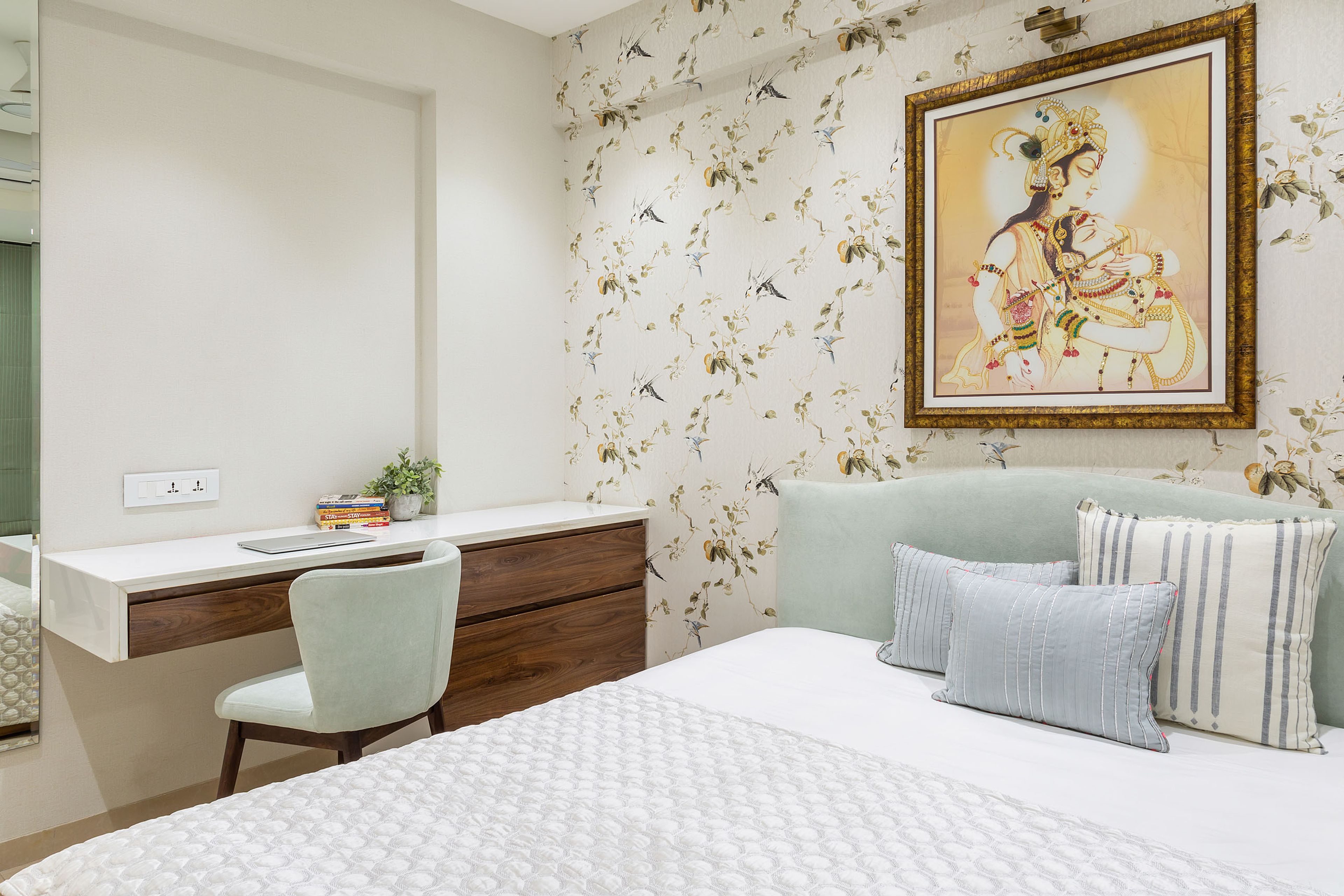 Guest bedroom with floral wallpaper and wall decor plus a  work table with storage unit - Livspace