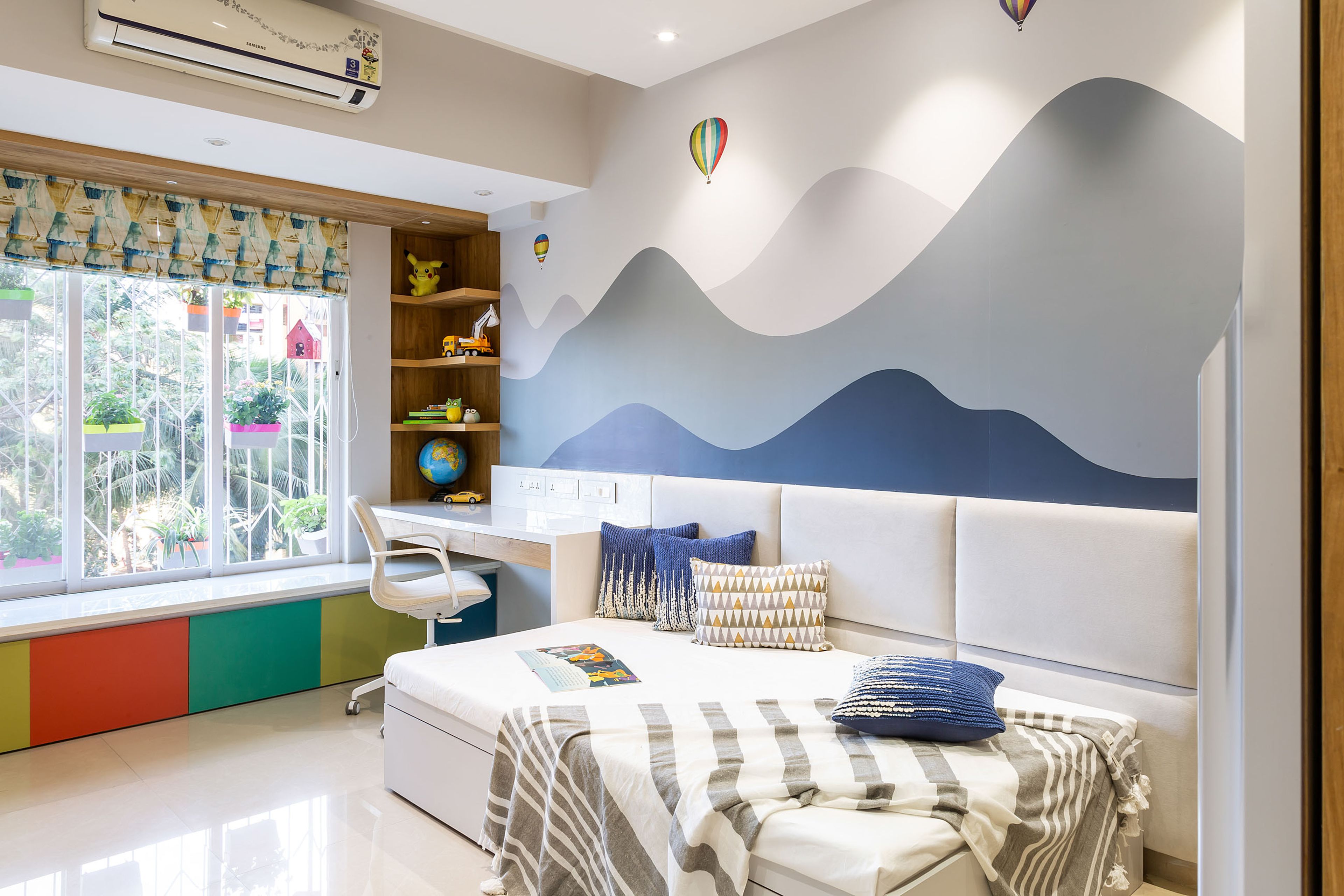 Kids bedroom with sky themed wallpaper and multi colur storage unit with L-shaped open wall units - Livspace