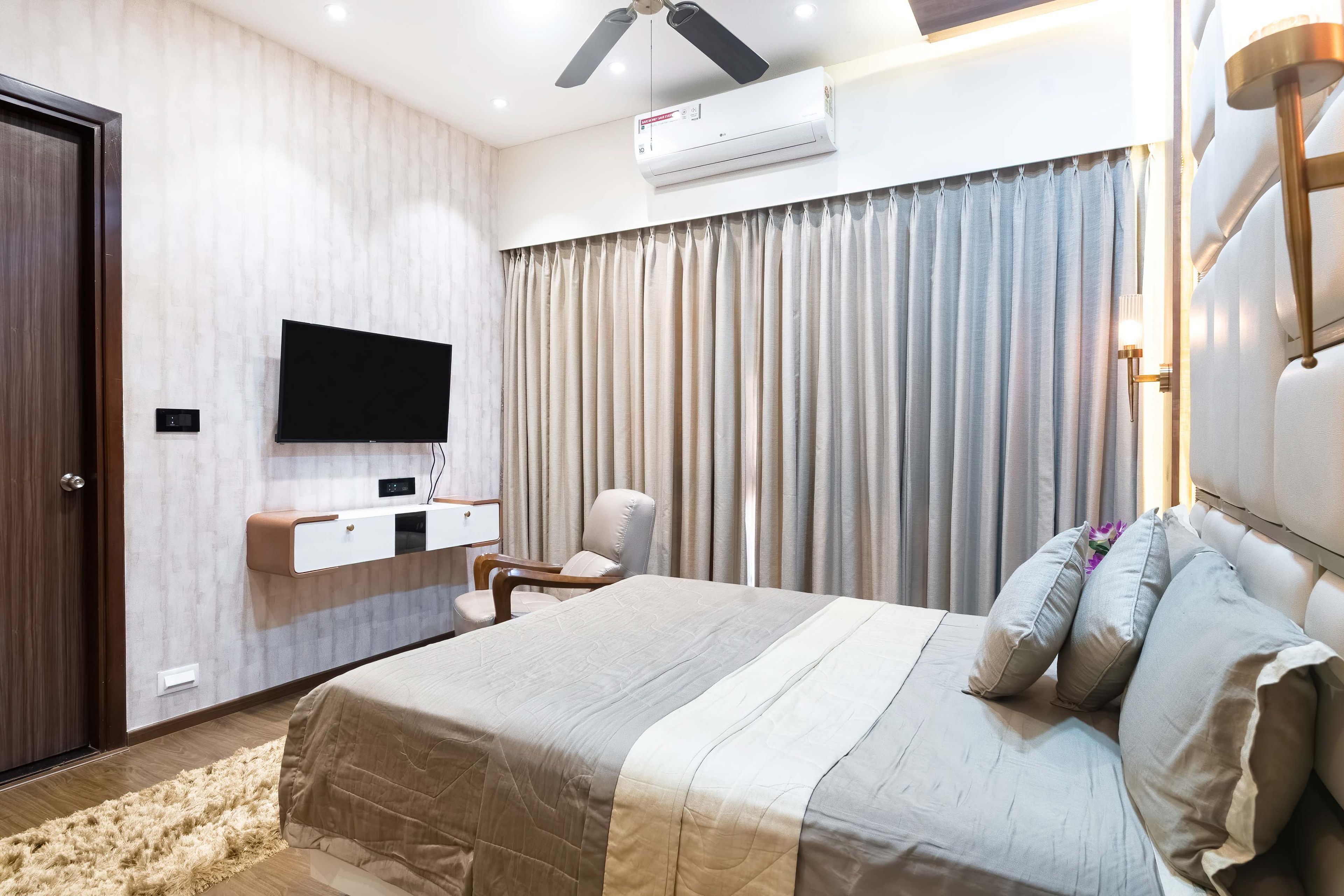 Grey bed for the guest bedroom and a white and wood TV unit - Livspace