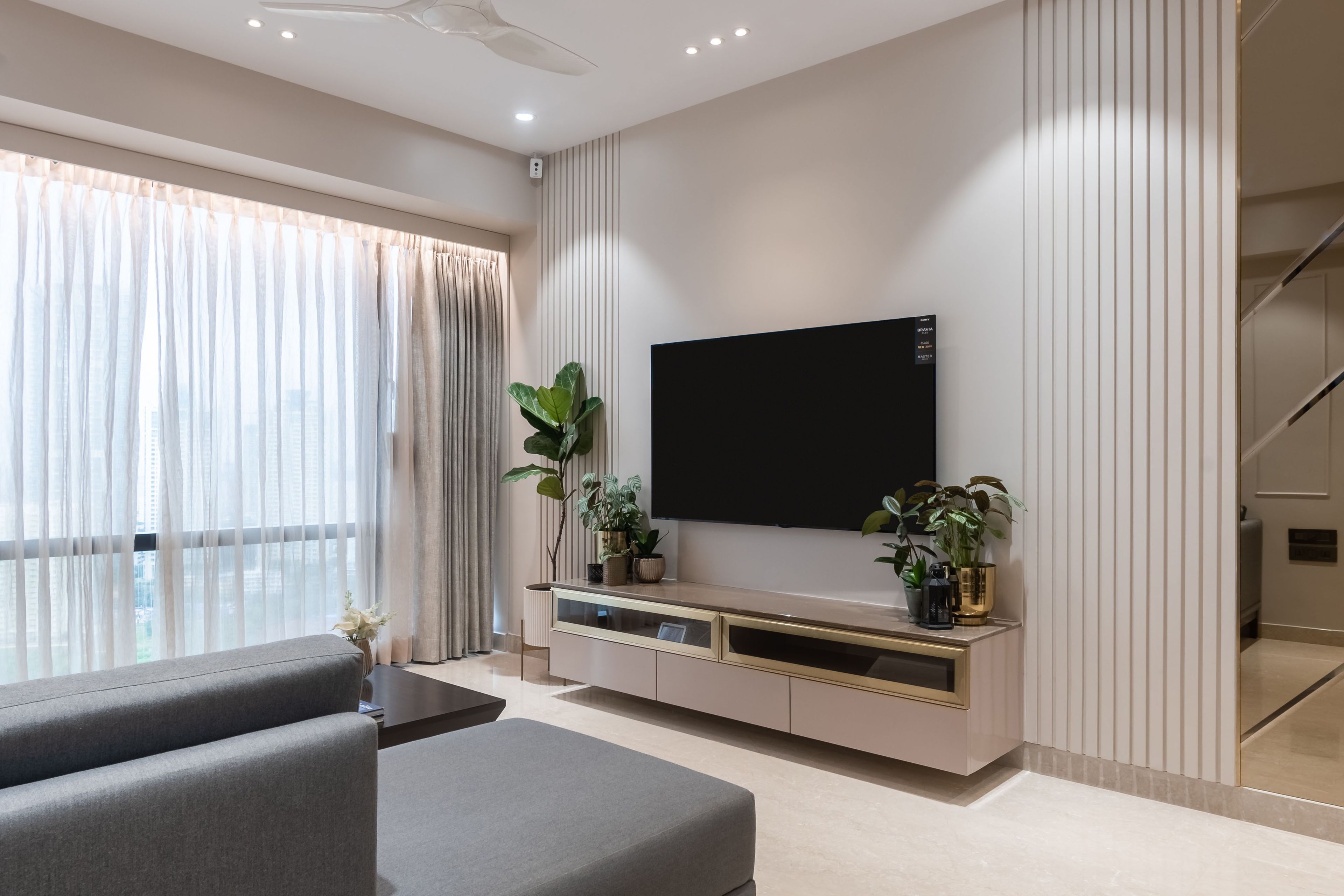 Light pink and gold TV unit design with light pink wall panels - Livspace