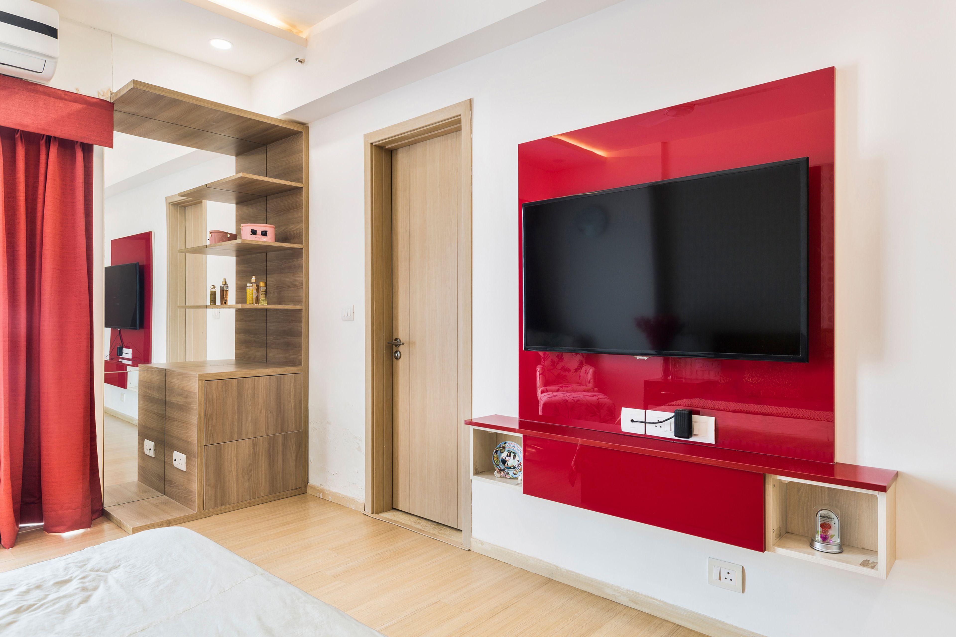 Red and white wall-mounted bedroom TV unit design - Livspace