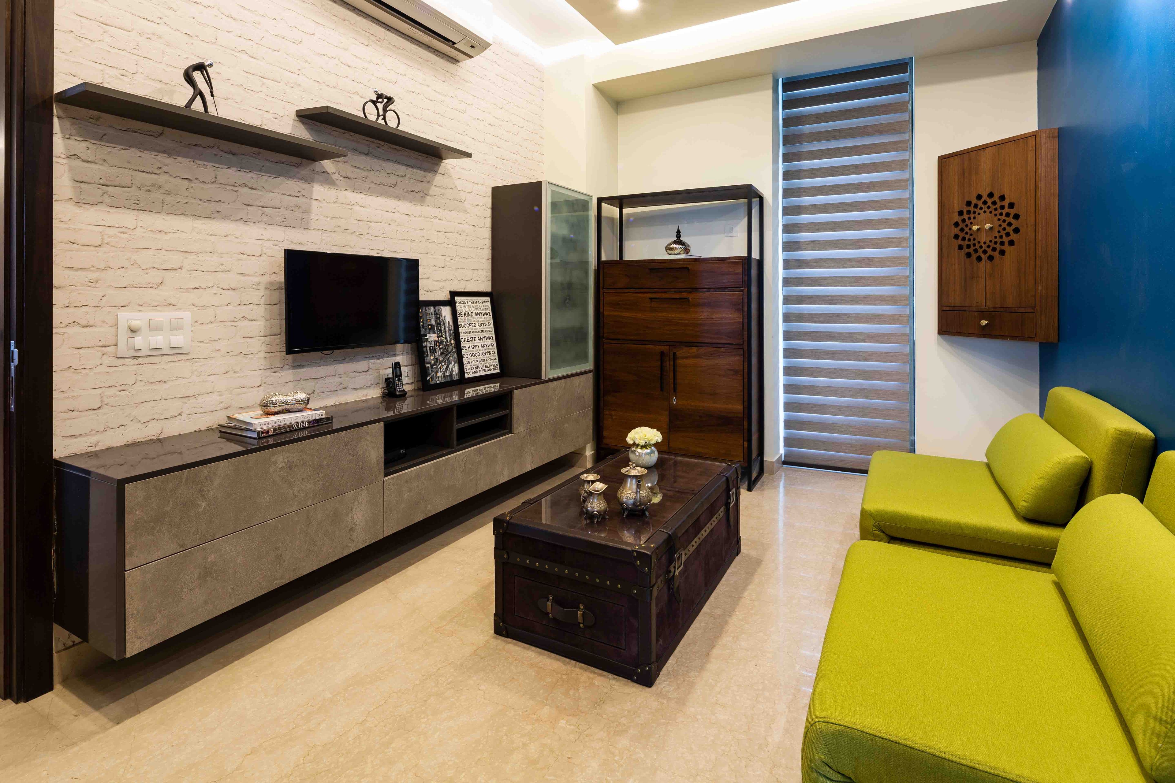Family room with neon green seaters, white brick wall and TV unit - Livspace