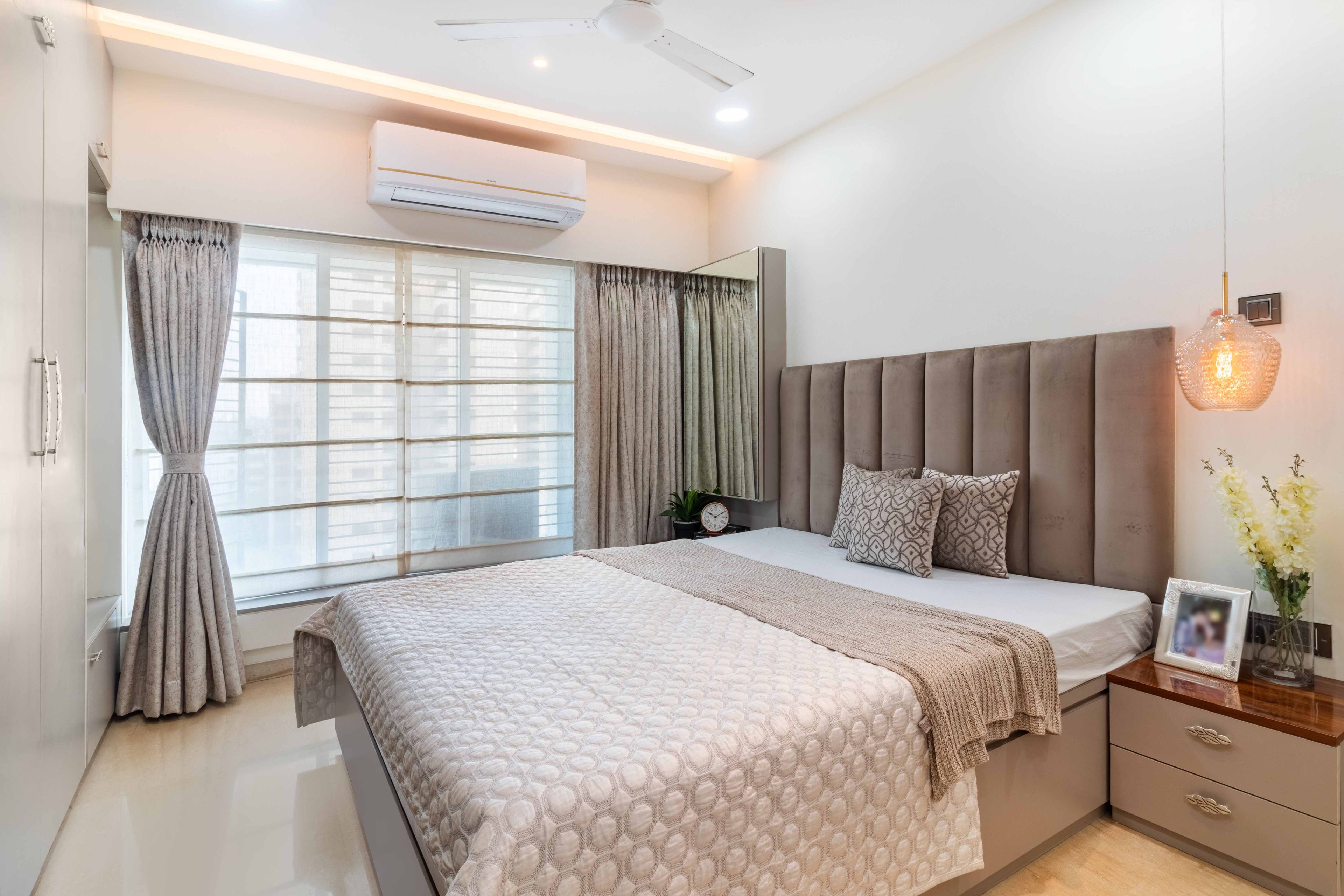 Guest bedroom with brown tufted headboard and bedside stand - Livspace