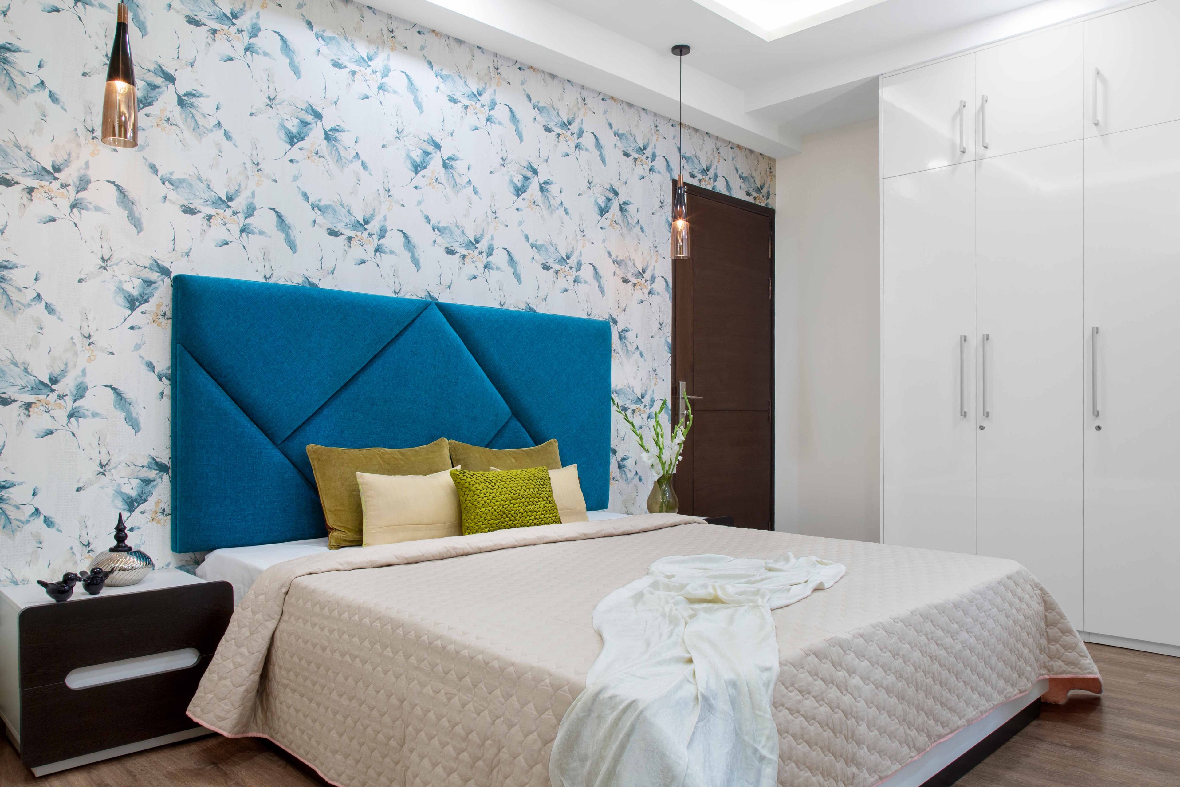 Master bedroom with blue and white floral wallpaper and blue headboard - Livspace