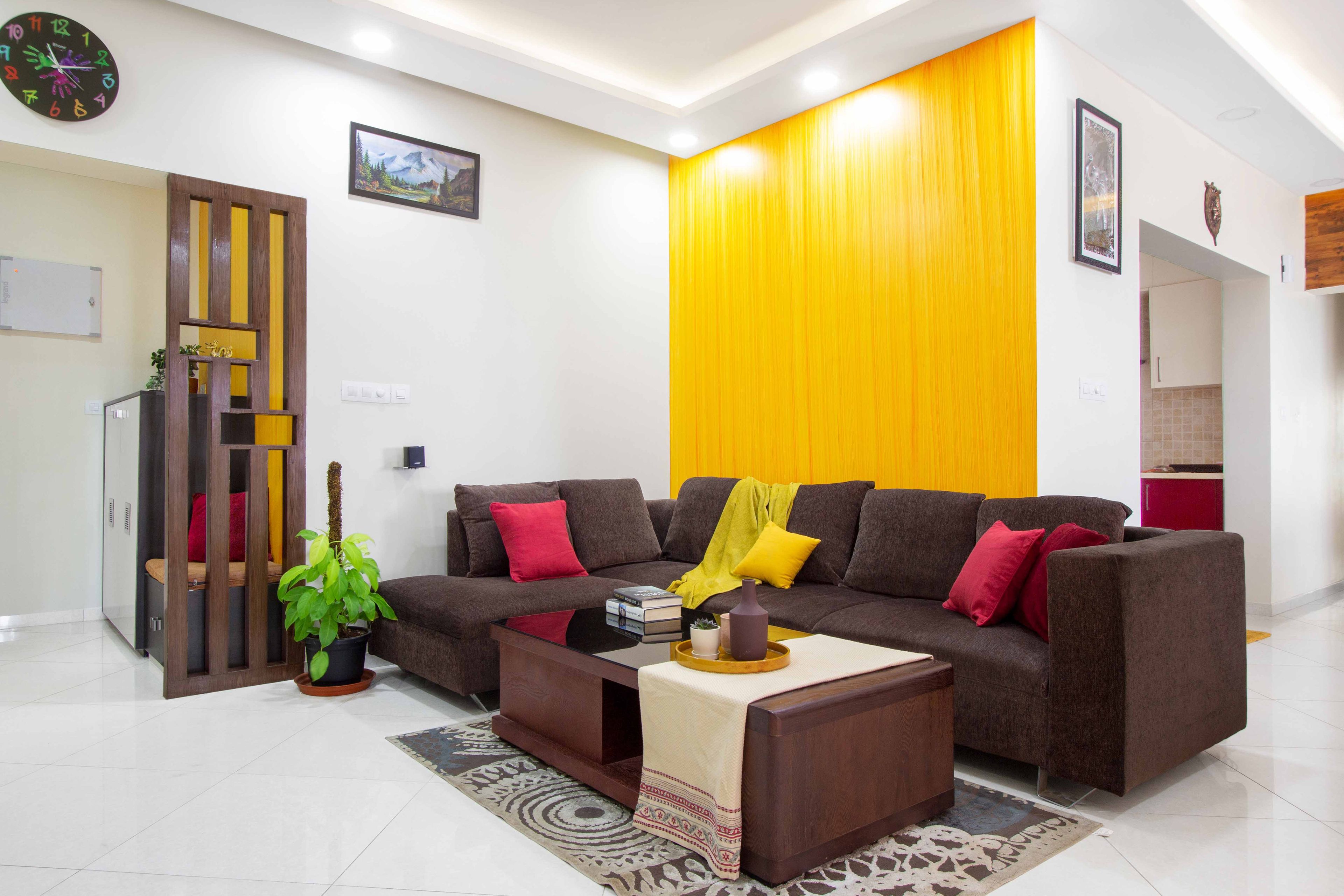 Dark brown L shaped sofa with yellow accent wall - Livspace