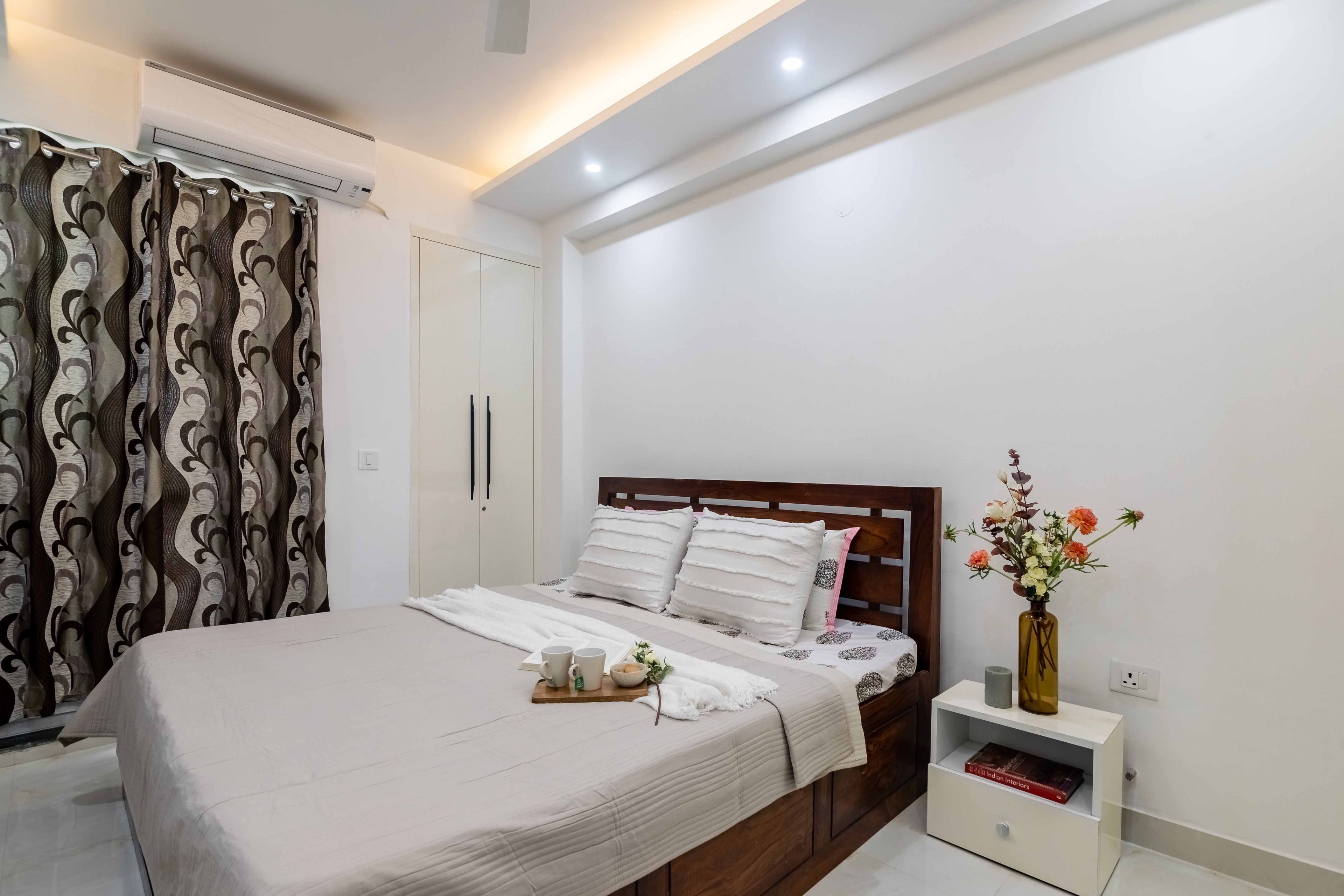 Queen-sized wooden bed for the master bedroom, with white upholstery - Livspace