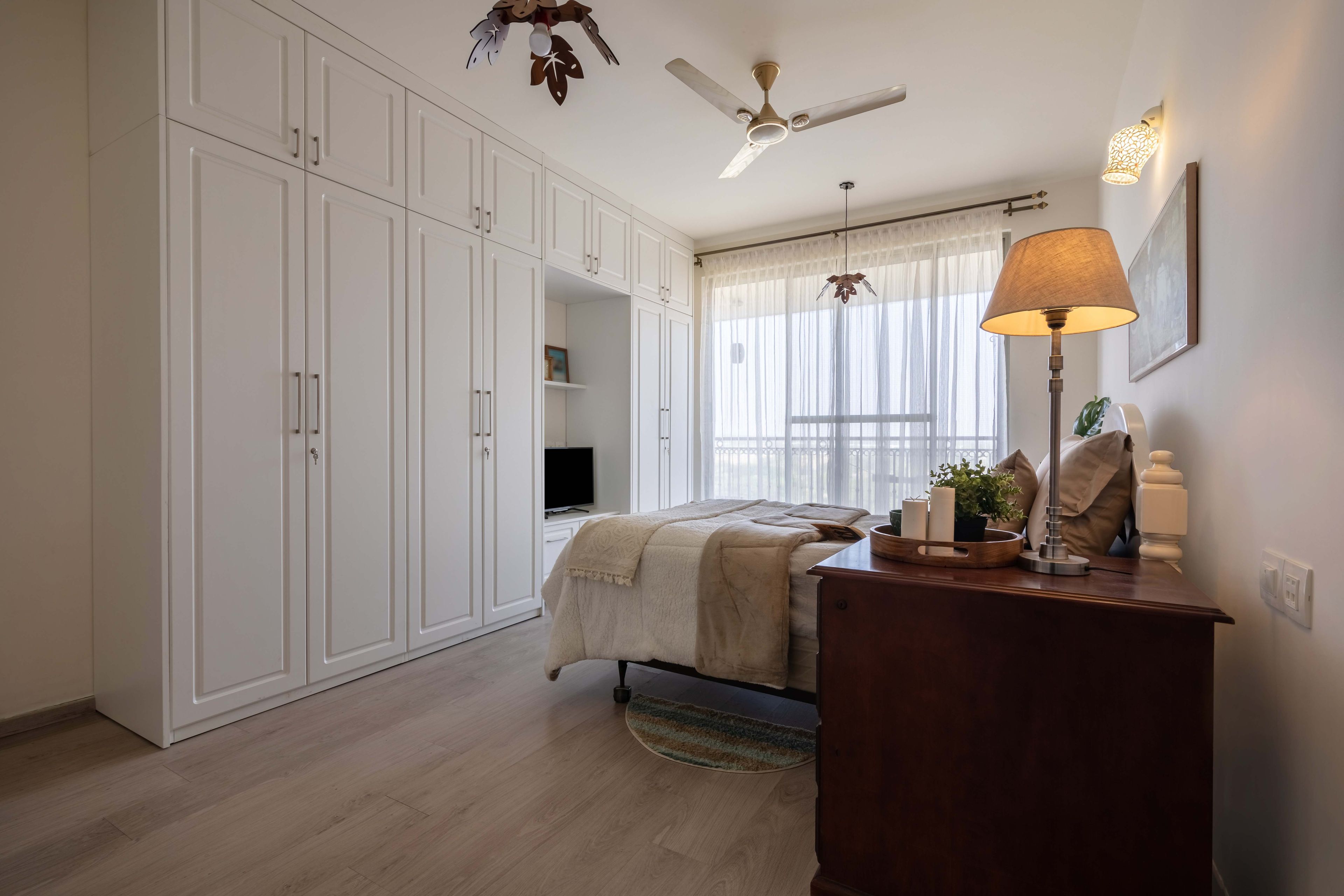 Master bedroom with white 6-door swing wardrobe with loft storage and integrated TV unit - Livspace