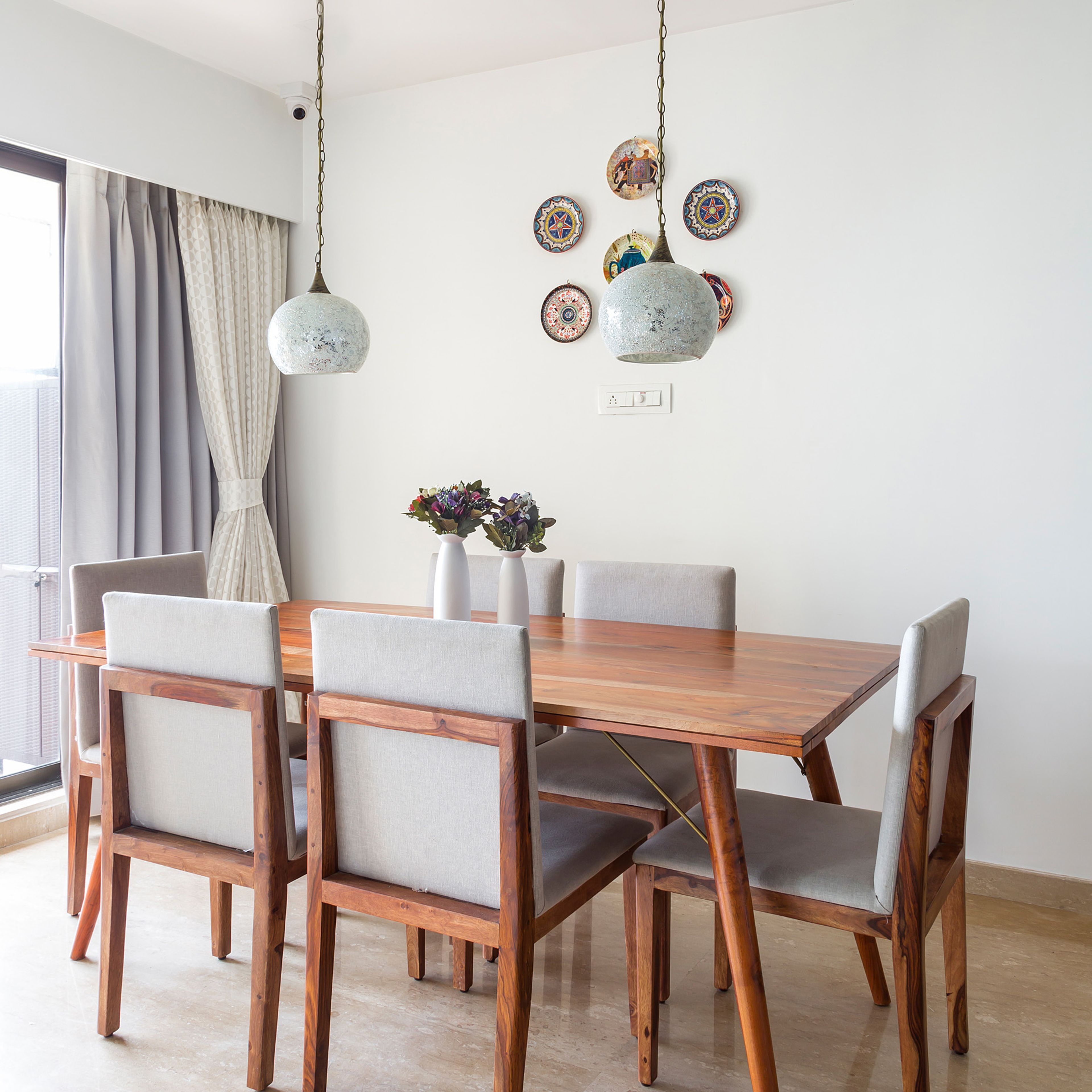 6-seater wooden dining table with armless cushioned chair with drop lights - Livspace