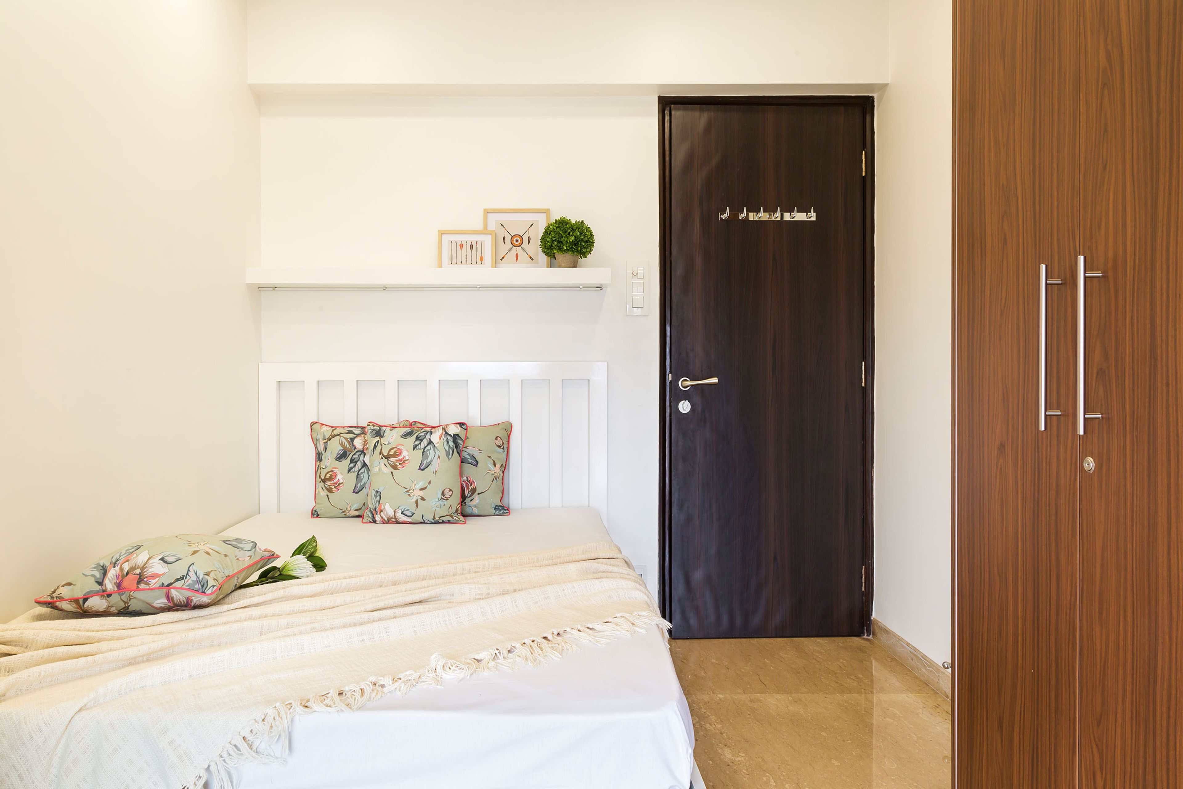 Kids’ bedroom with 2-door wooden swing wardrobe and white cot - Livspace