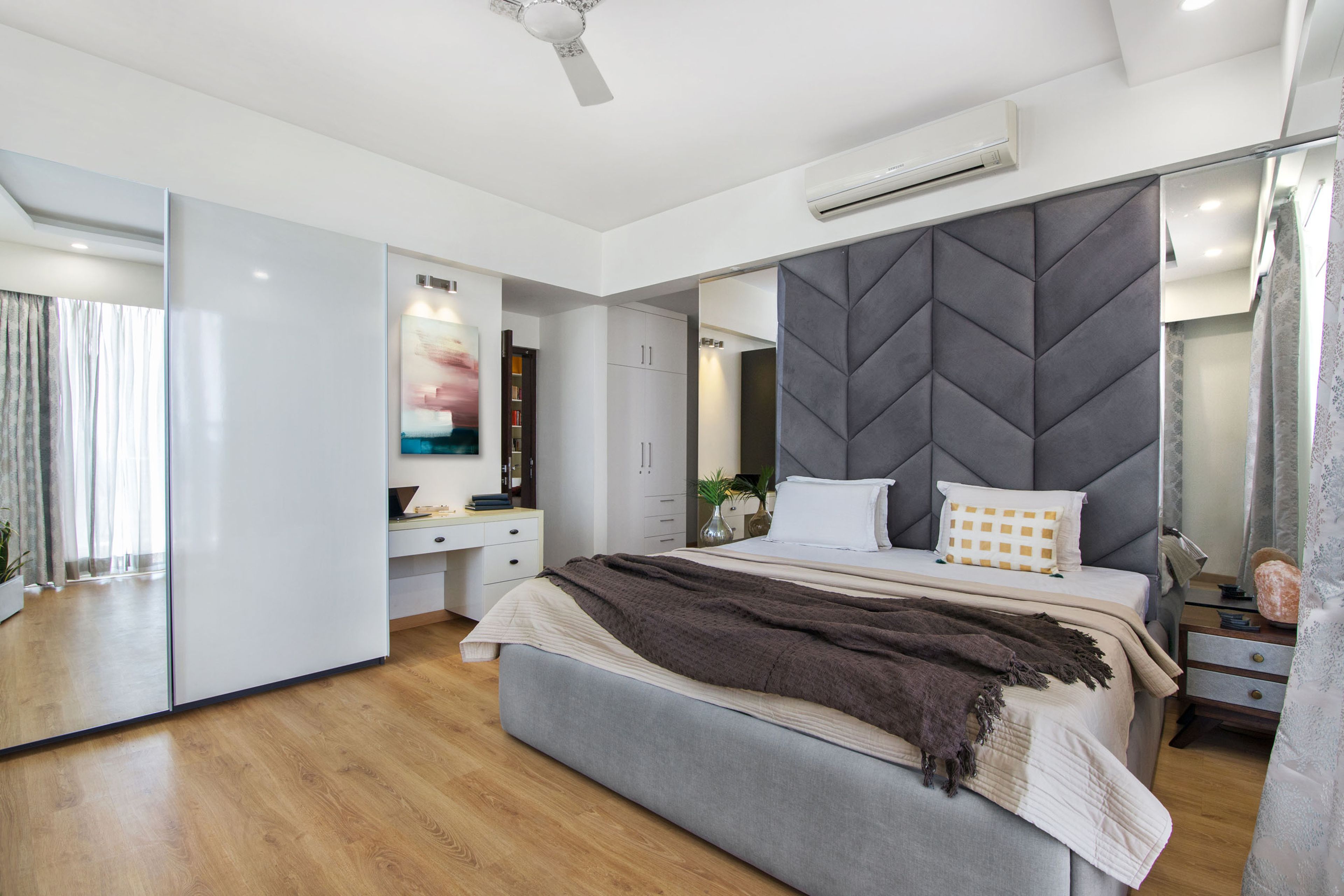 Grey and white master bedroom with large grey headboard - Livspace