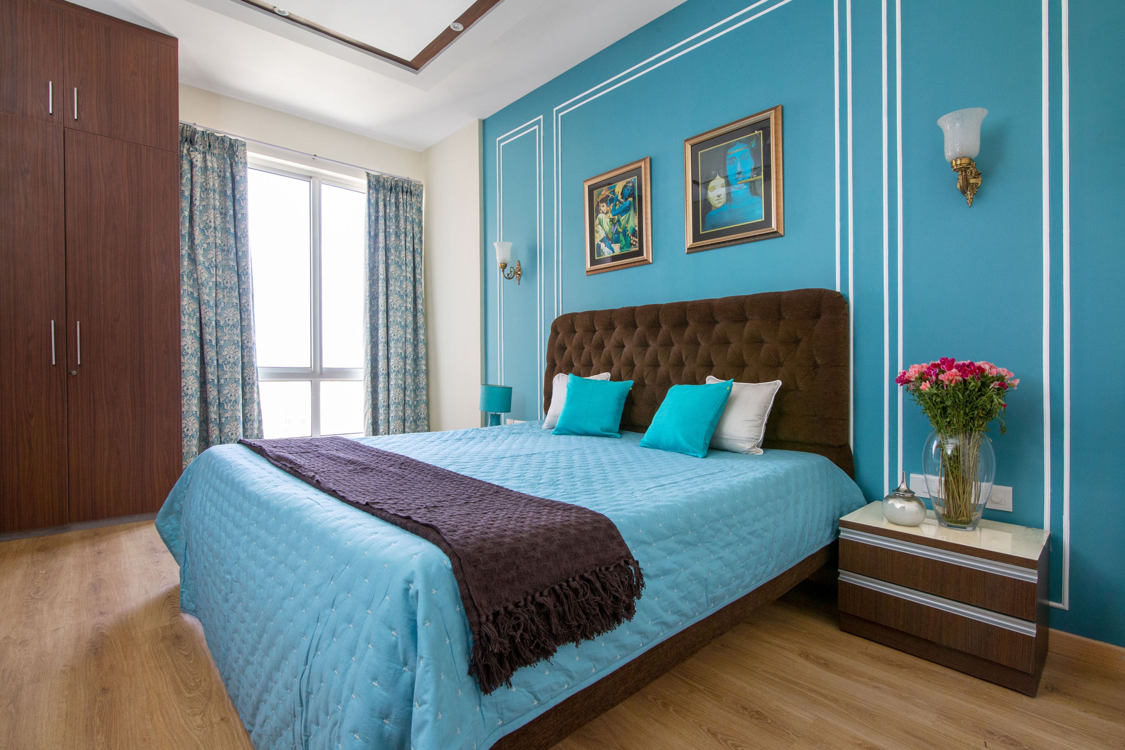 Bright blue guest room design with dark wood wardrobe and brown headboard - Livspace
