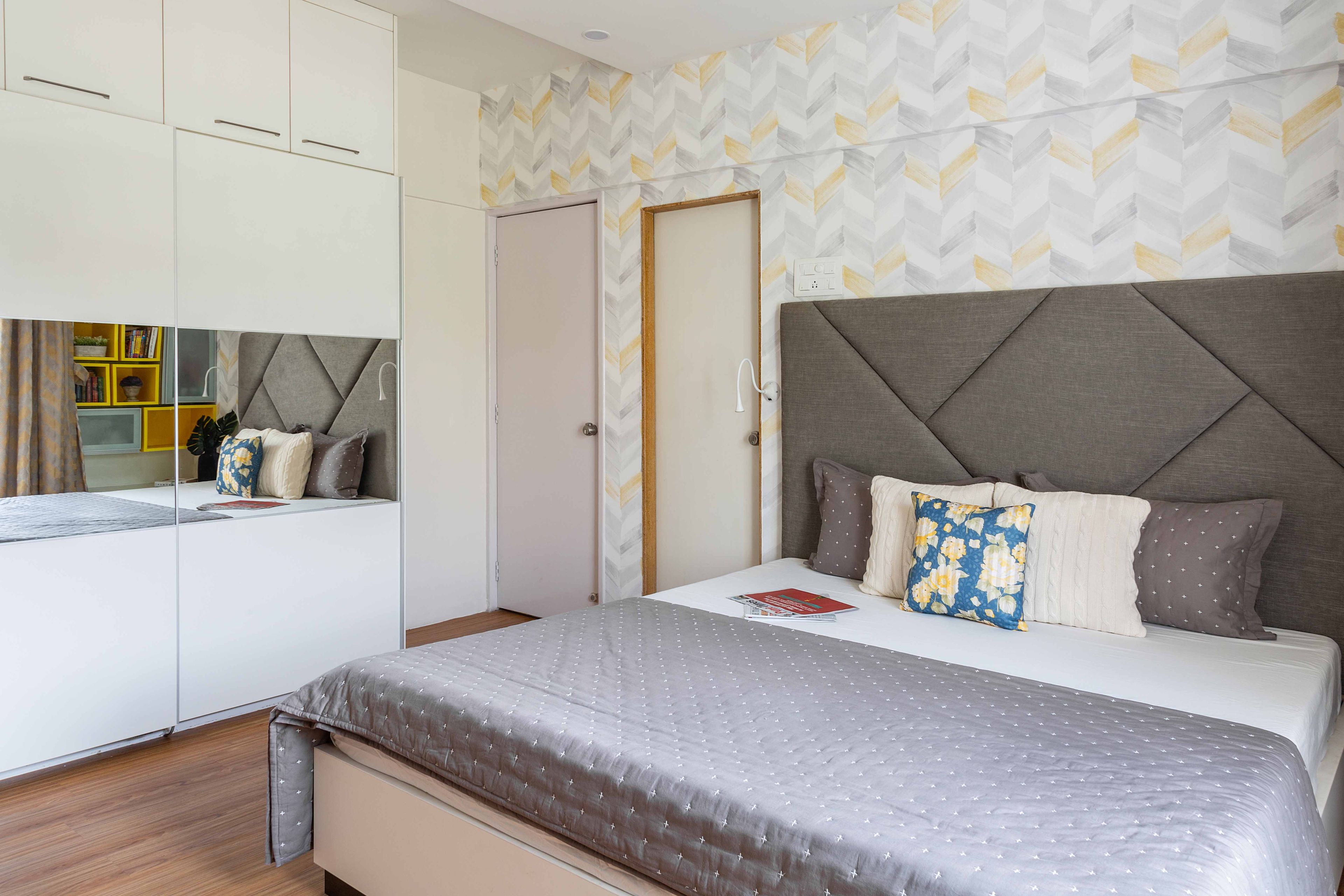 Master bedroom with grey headboard bed and white, mirrored sliidng wardrobe - Livspace