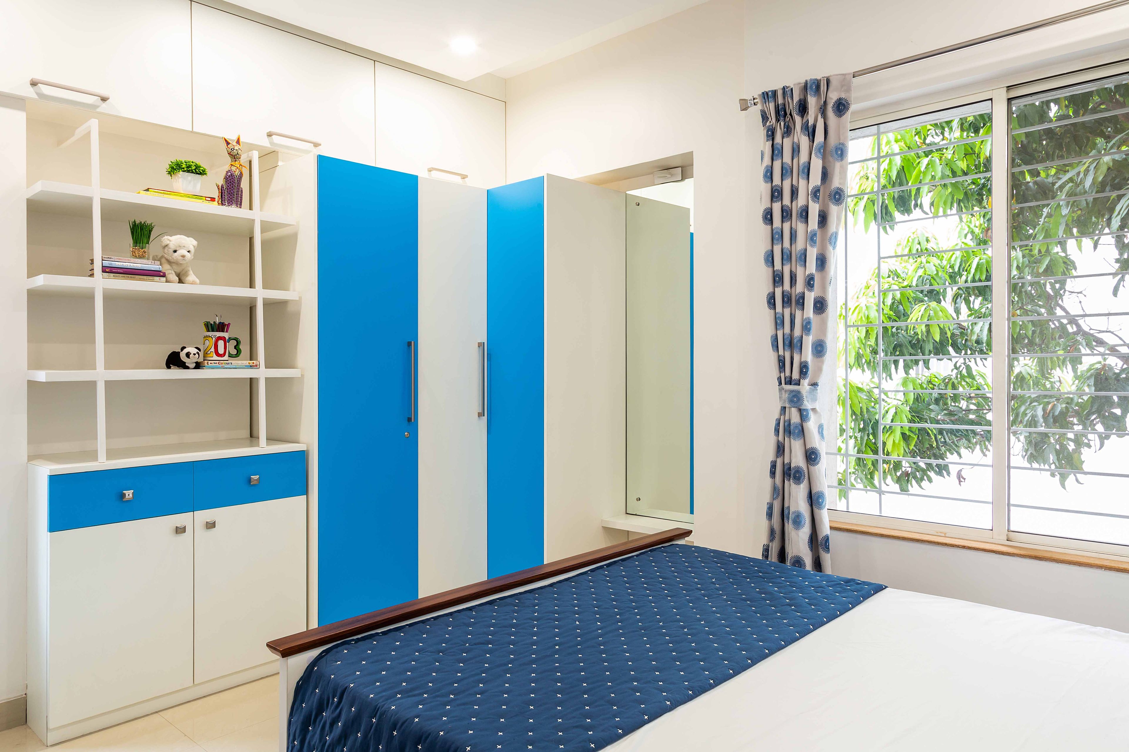 L shaped blue and white wardrobe design for kids bedroom and open storage unit - Livspace