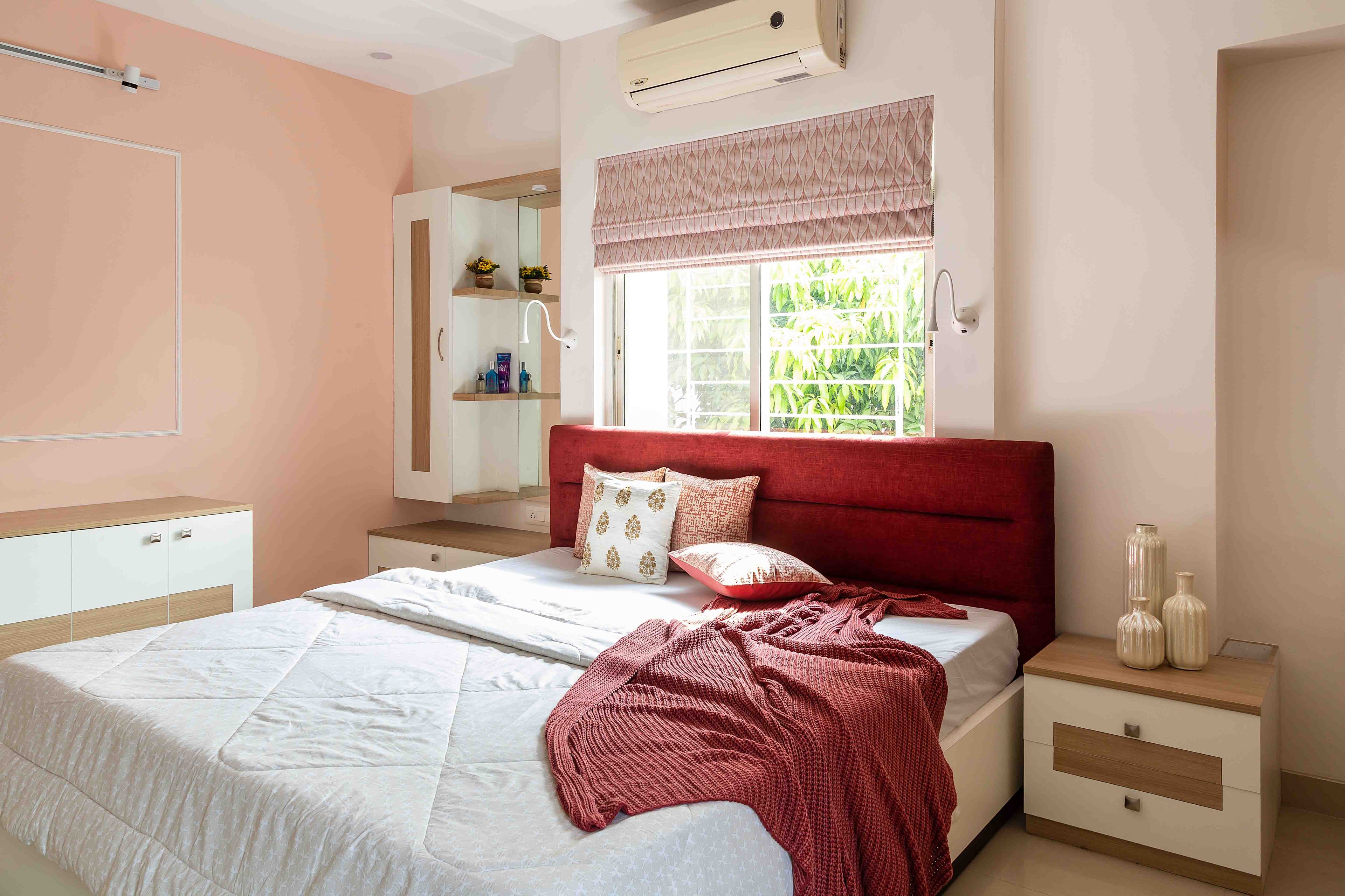 Guest room with light pink interiors and rust orange headboard - Livspace