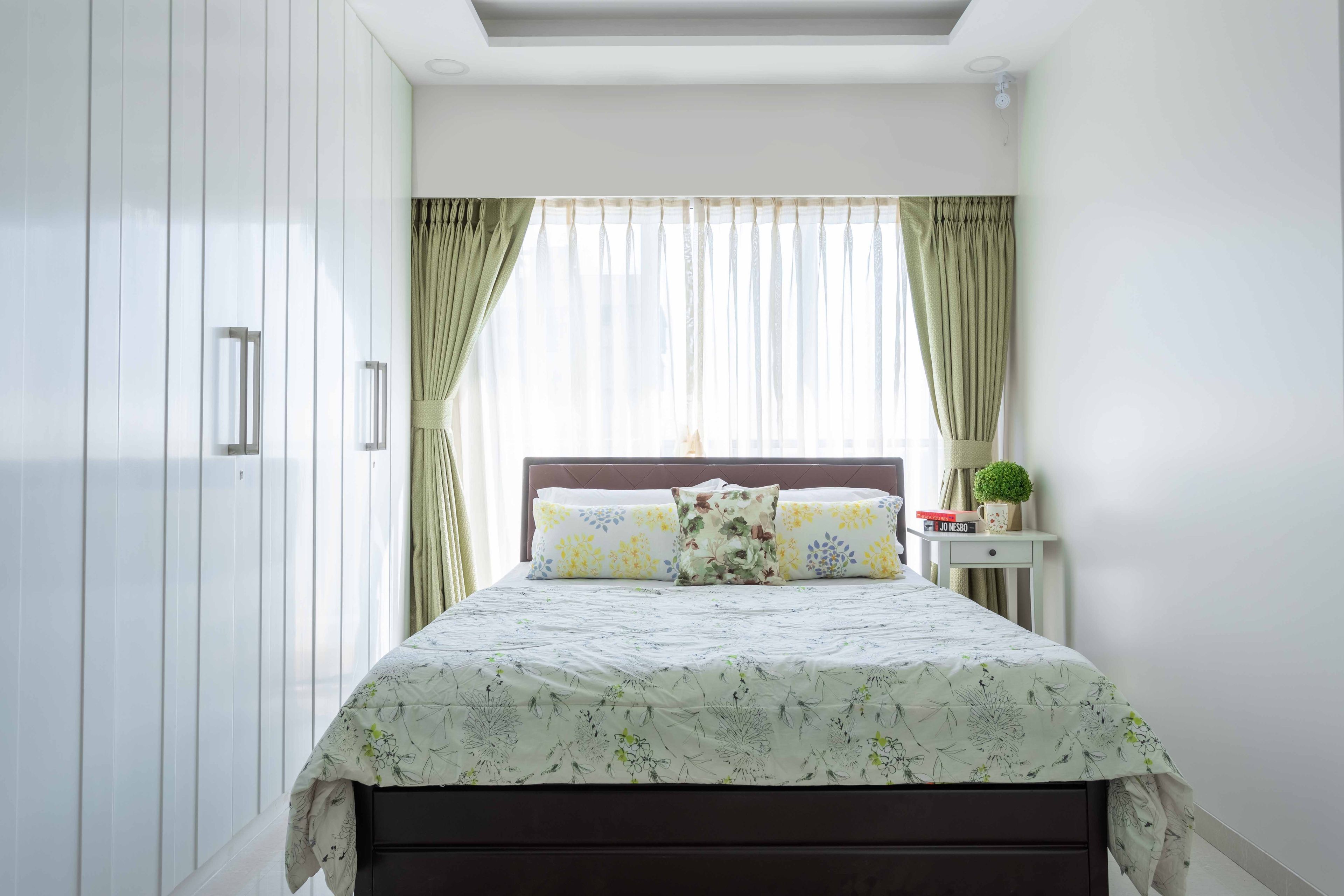 A bedroom with white tufted headboard and a 4-door swing wardrobe - Livspace