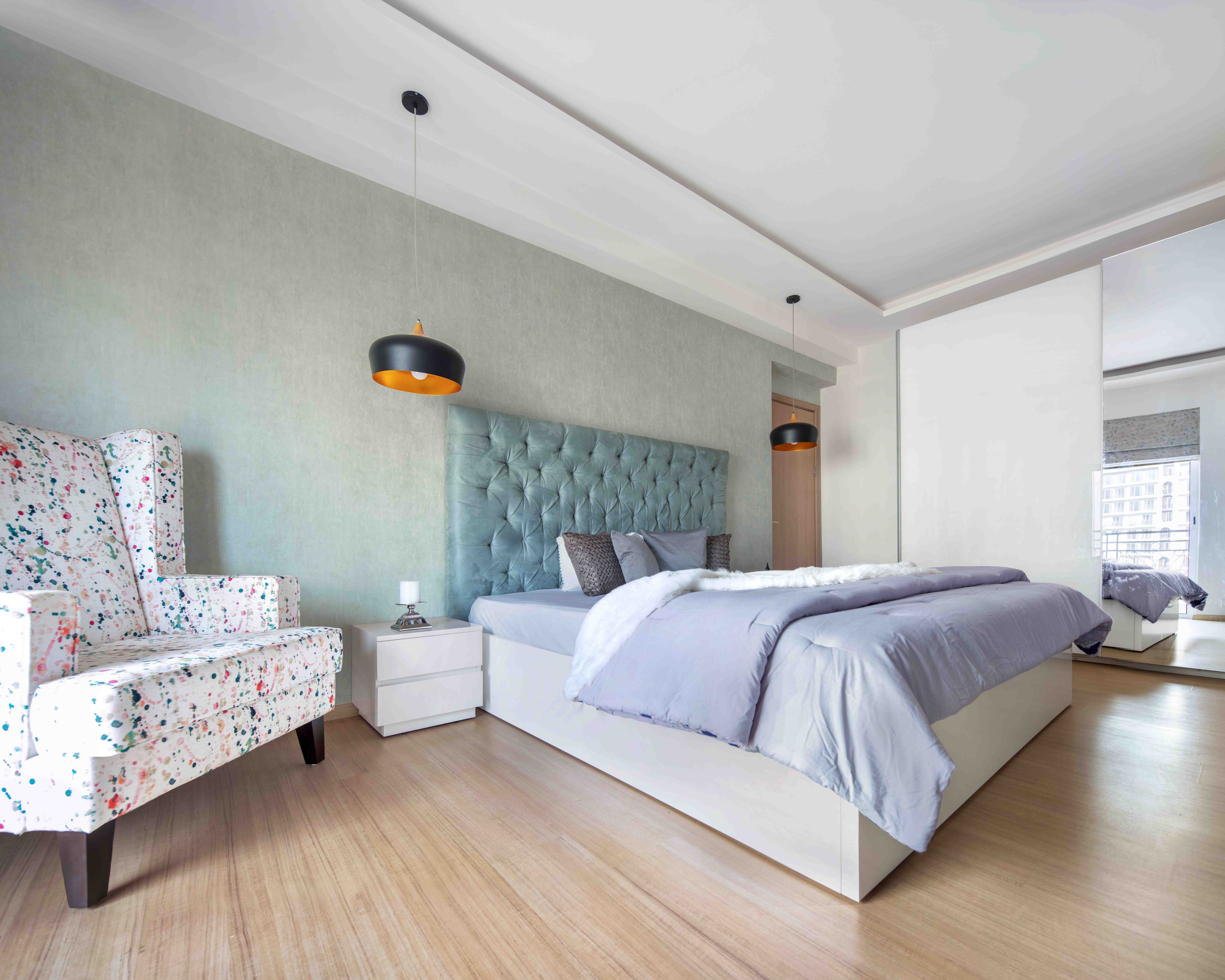 Spacious master bedroom with light green accent wall and sliding wardrobe - Livspace