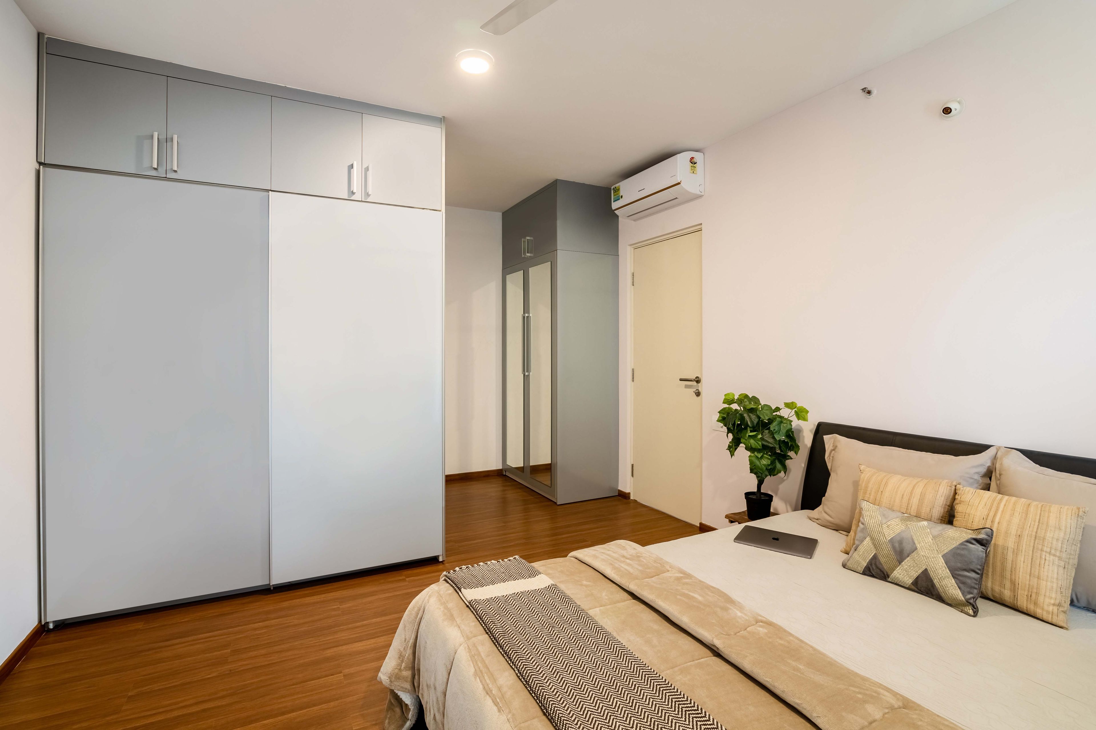 Master bedroom with dual-toned wardrobe and grey mirrored wardrobe - Livspace