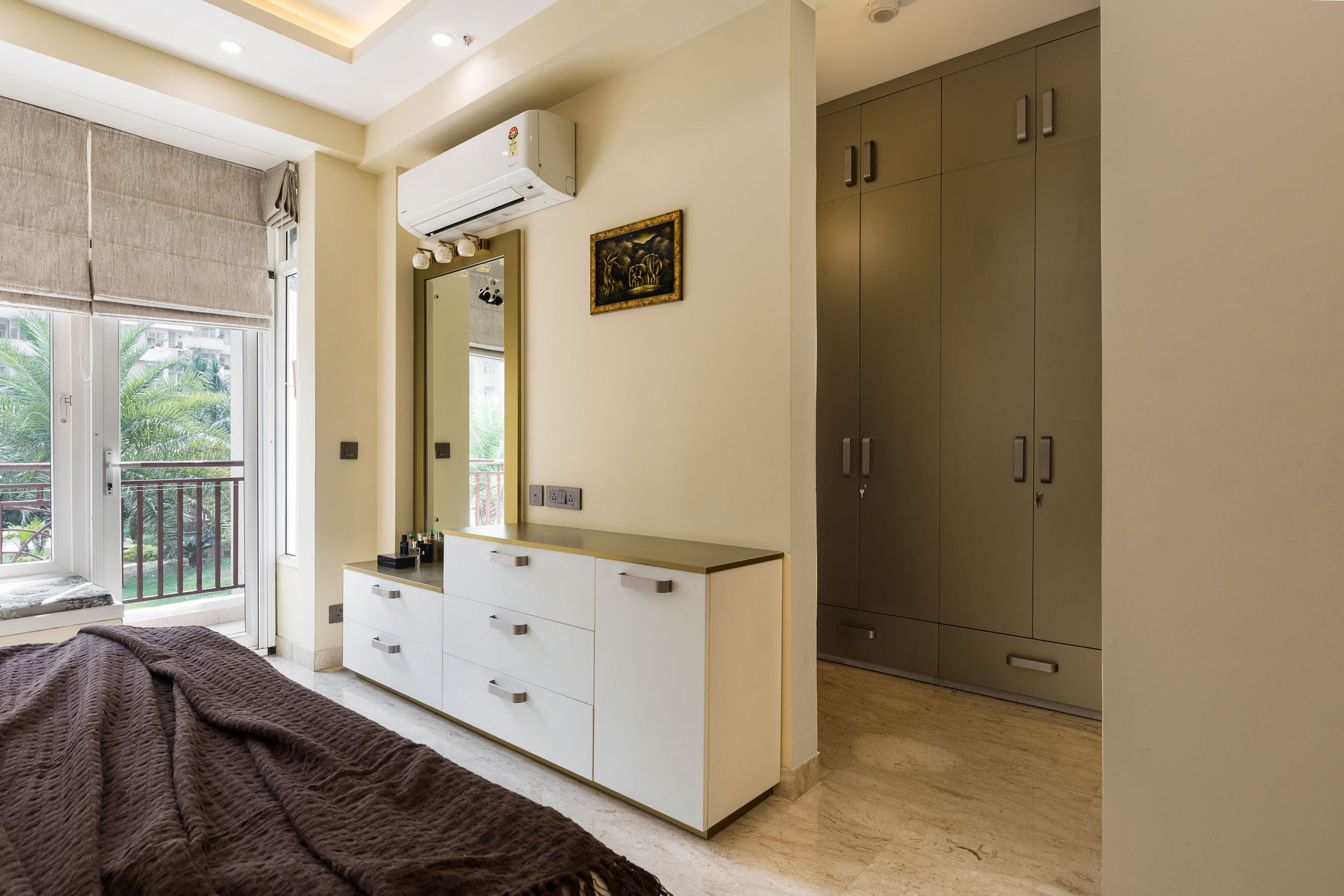 White stepped dressing unit and olive green 4-door swing wardrobe in a walk-in wardrobe layout - Livspace