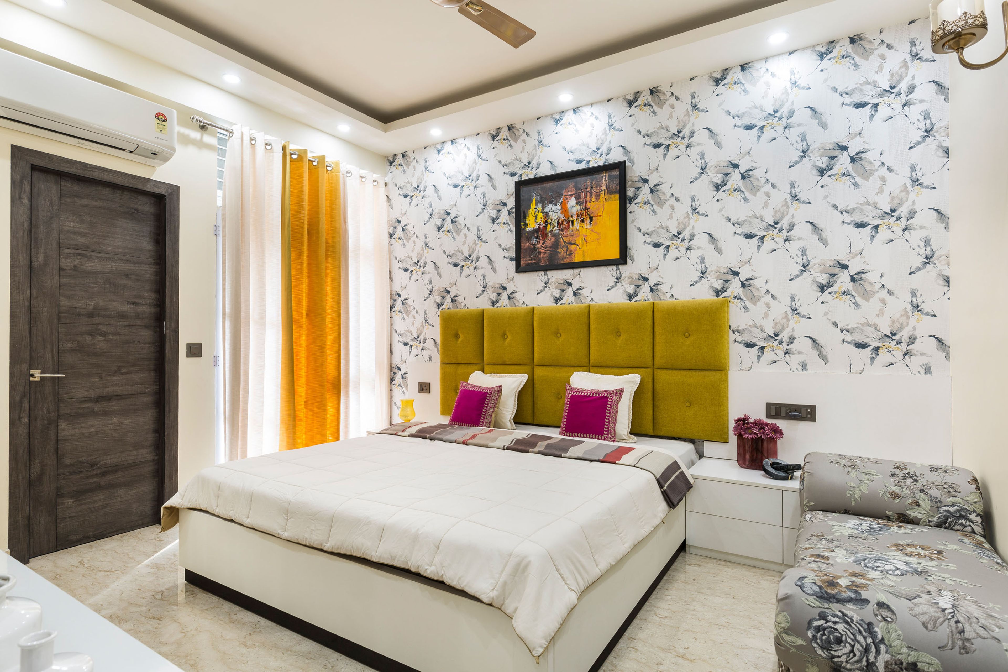 Guest room with queen sized bed and mustard headboard - Livspace