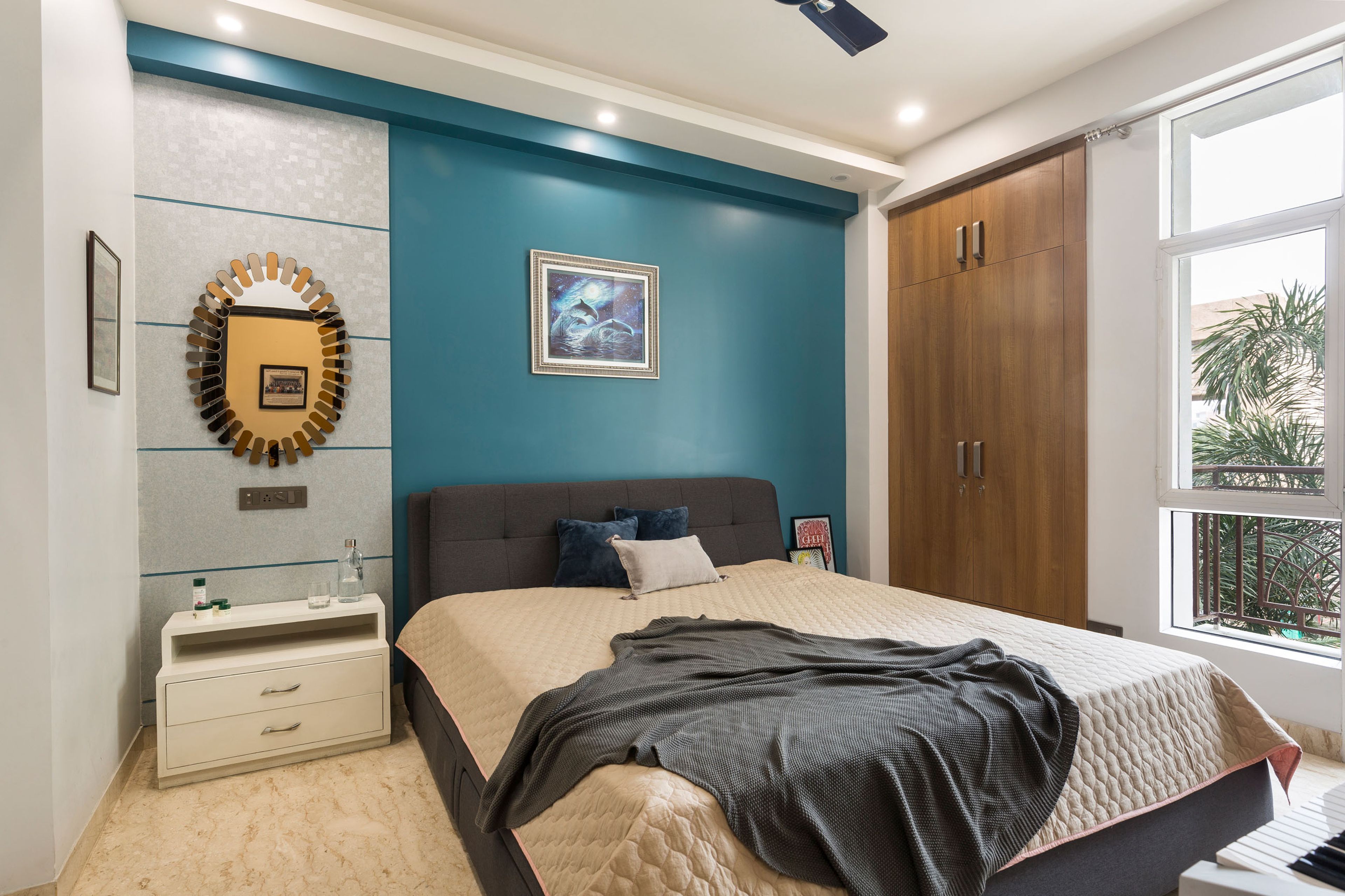 Second guest room with dark blue accent wall and wooden wardrobe - Livspace